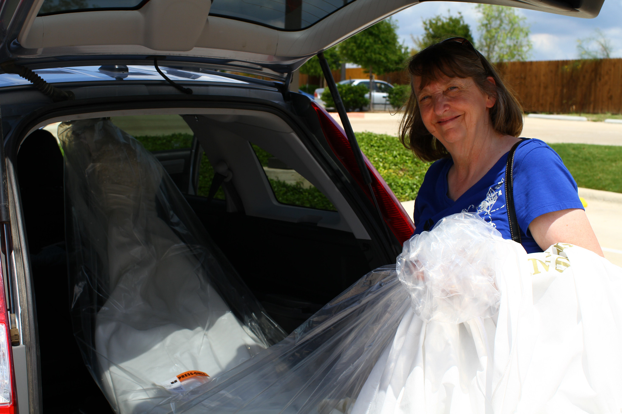 Una anciana sacando un vestido de novia del maletero de su automóvil | Fuente: Flickr