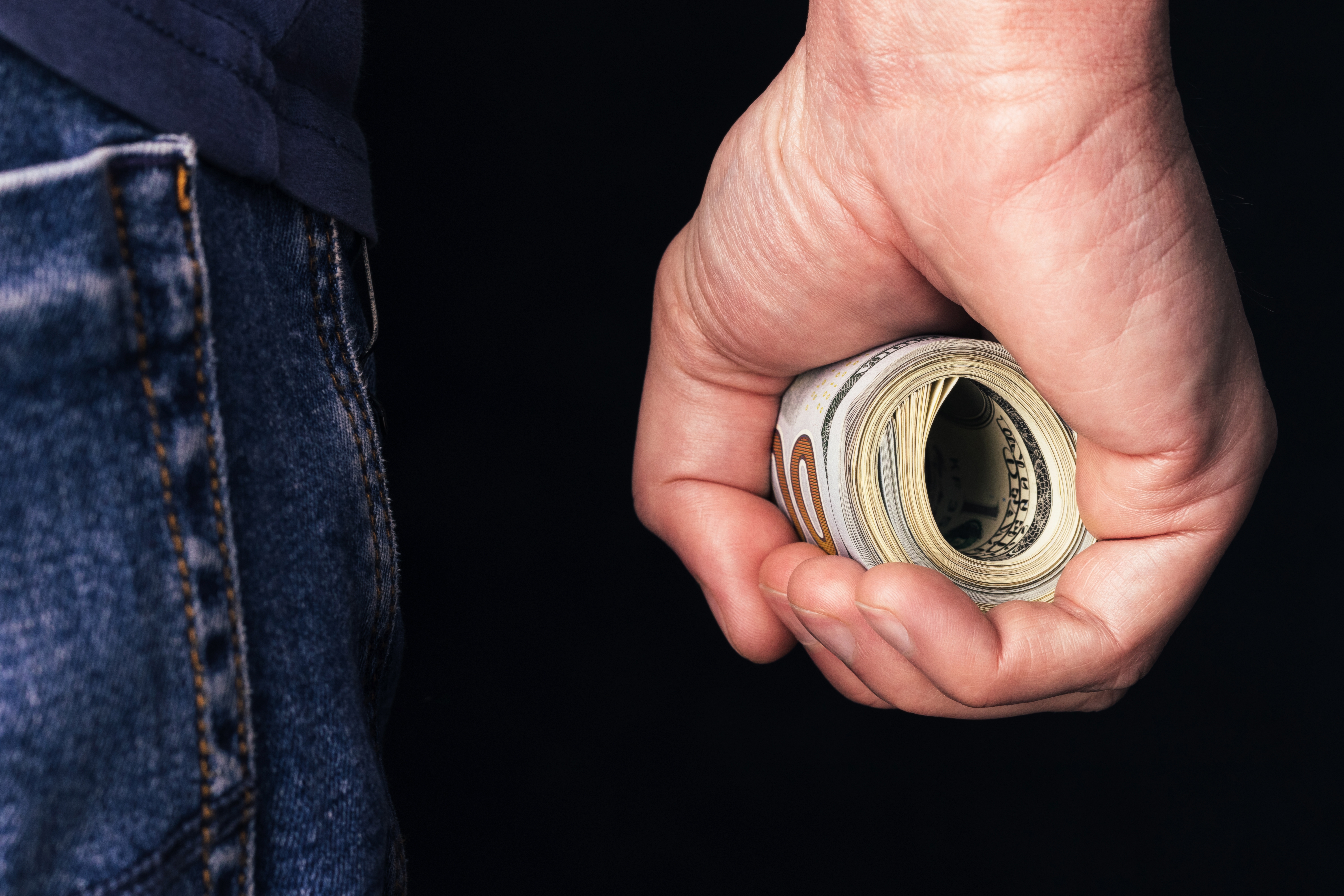 Rollo de billetes dólares en una mano | Foto: Shutterstock