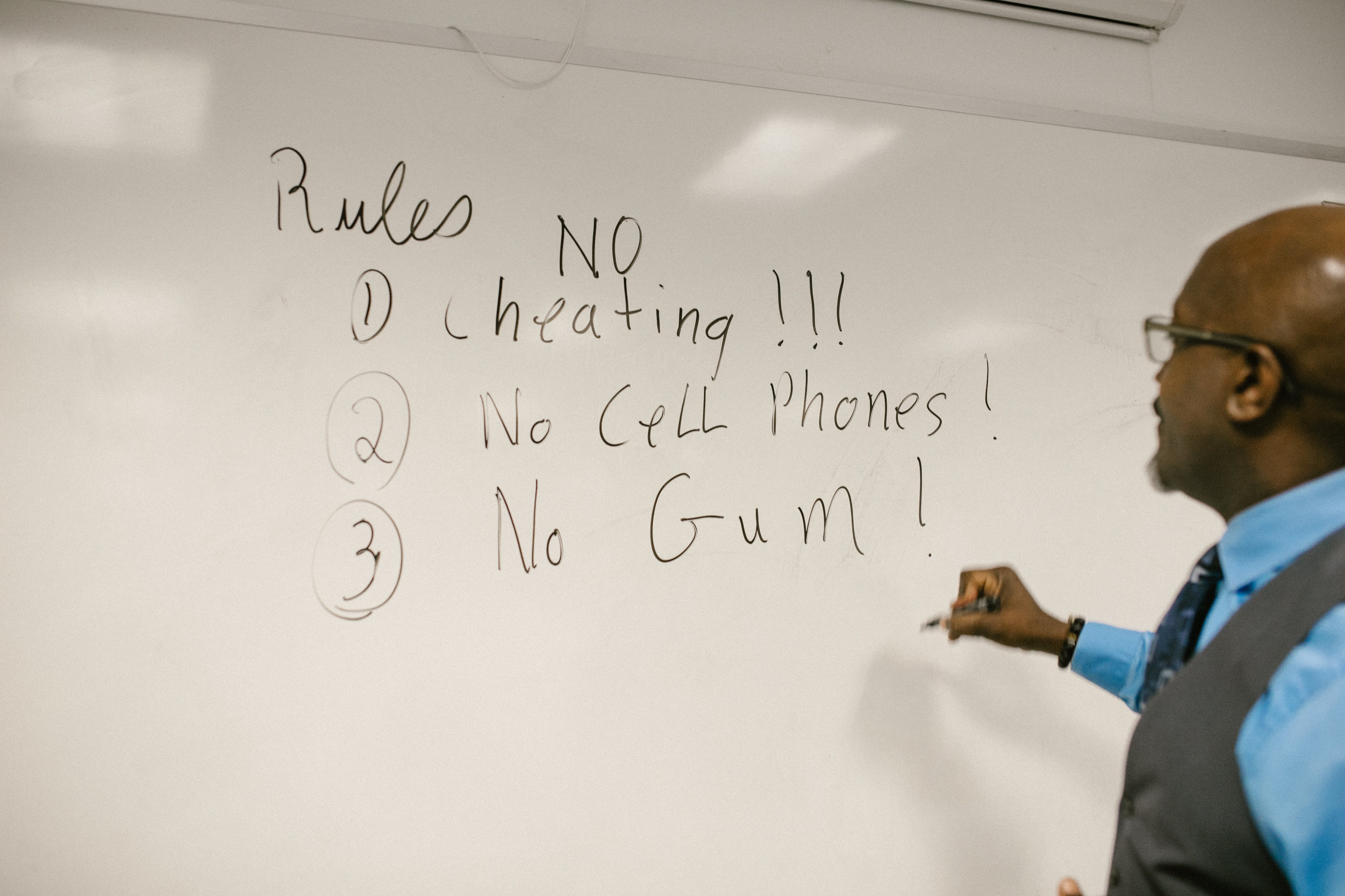 A man writing down rules on a whiteboard. | Source: Pexels