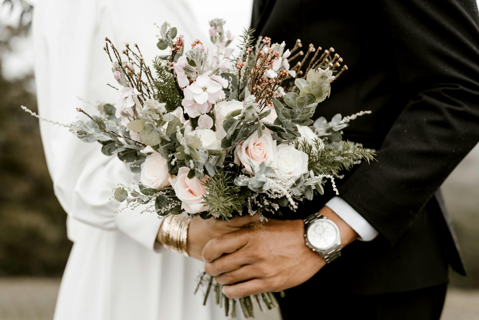 Una pareja sosteniendo flores en su gran día | Fuente: Pexels