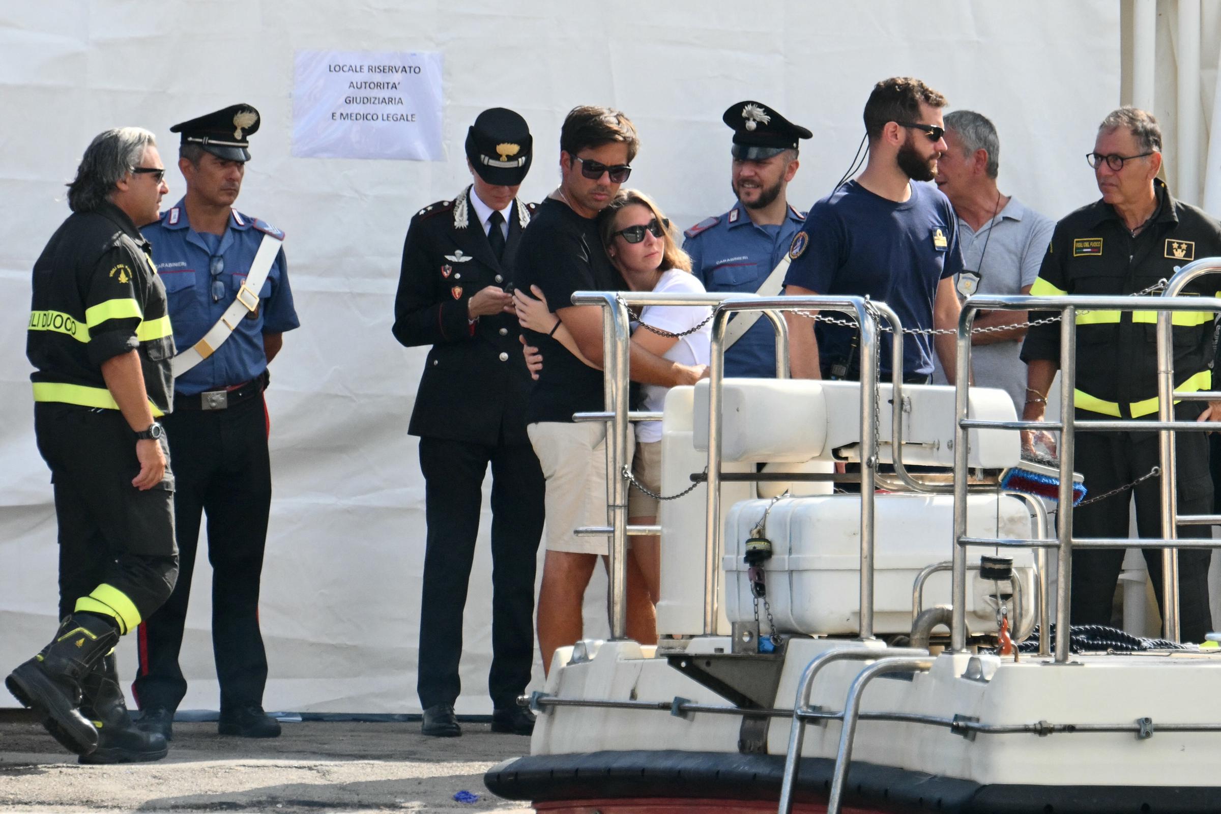 Varias personas se abrazan mientras observan a un equipo de búsqueda y rescate operar en el muelle de Porticello, Italia, el 22 de agosto de 2024, tres días después de que se hundiera el yate de lujo Bayesian, de bandera británica | Fuente: Getty Images