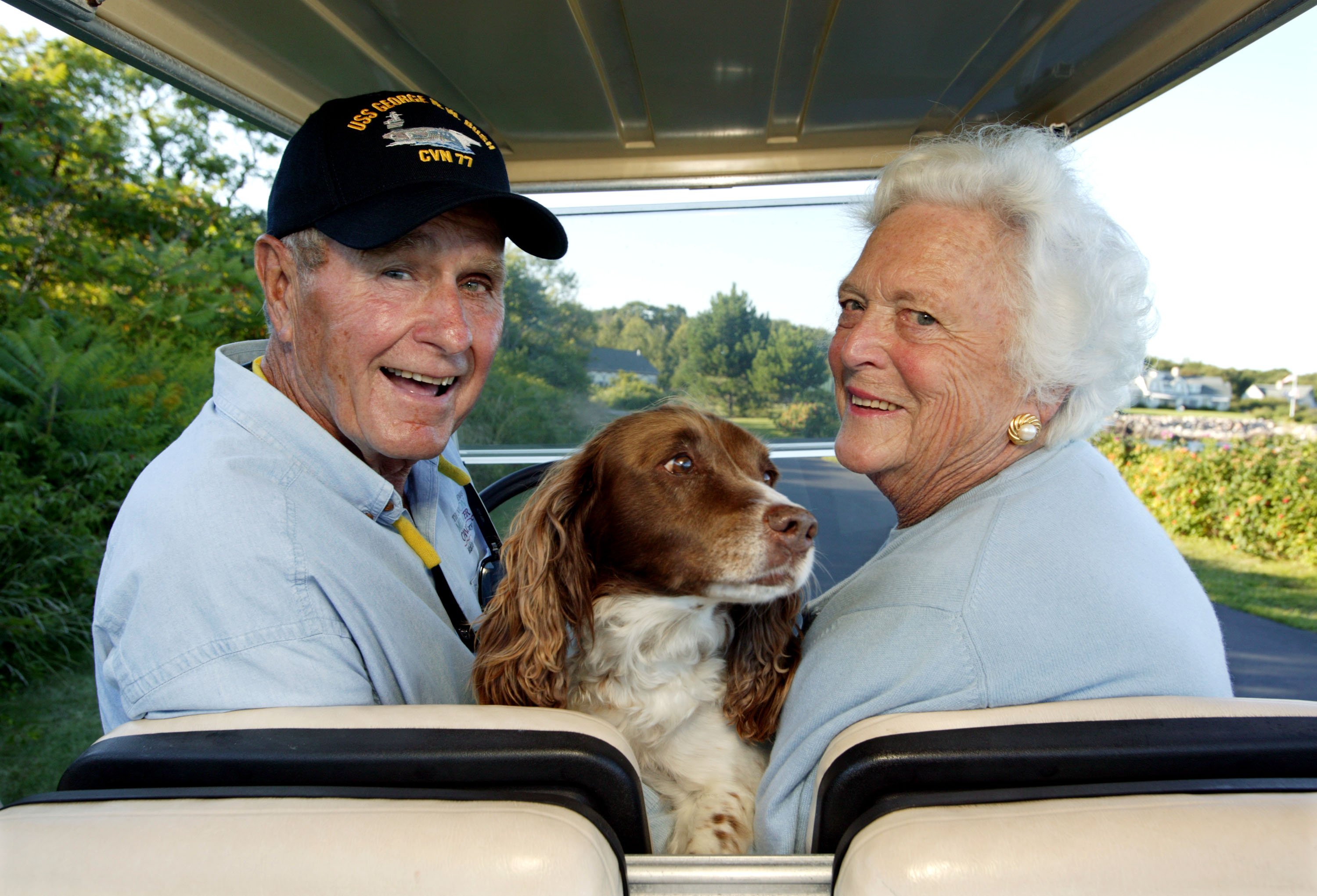 George H. W. Bush, y su esposa, Barbara, viajan en la parte trasera de un carrito de golf con su perro Millie en su casa en Walker's Point el 25 de agosto de 2004 en Kennebunkport, Maine. | Foto: Getty Images