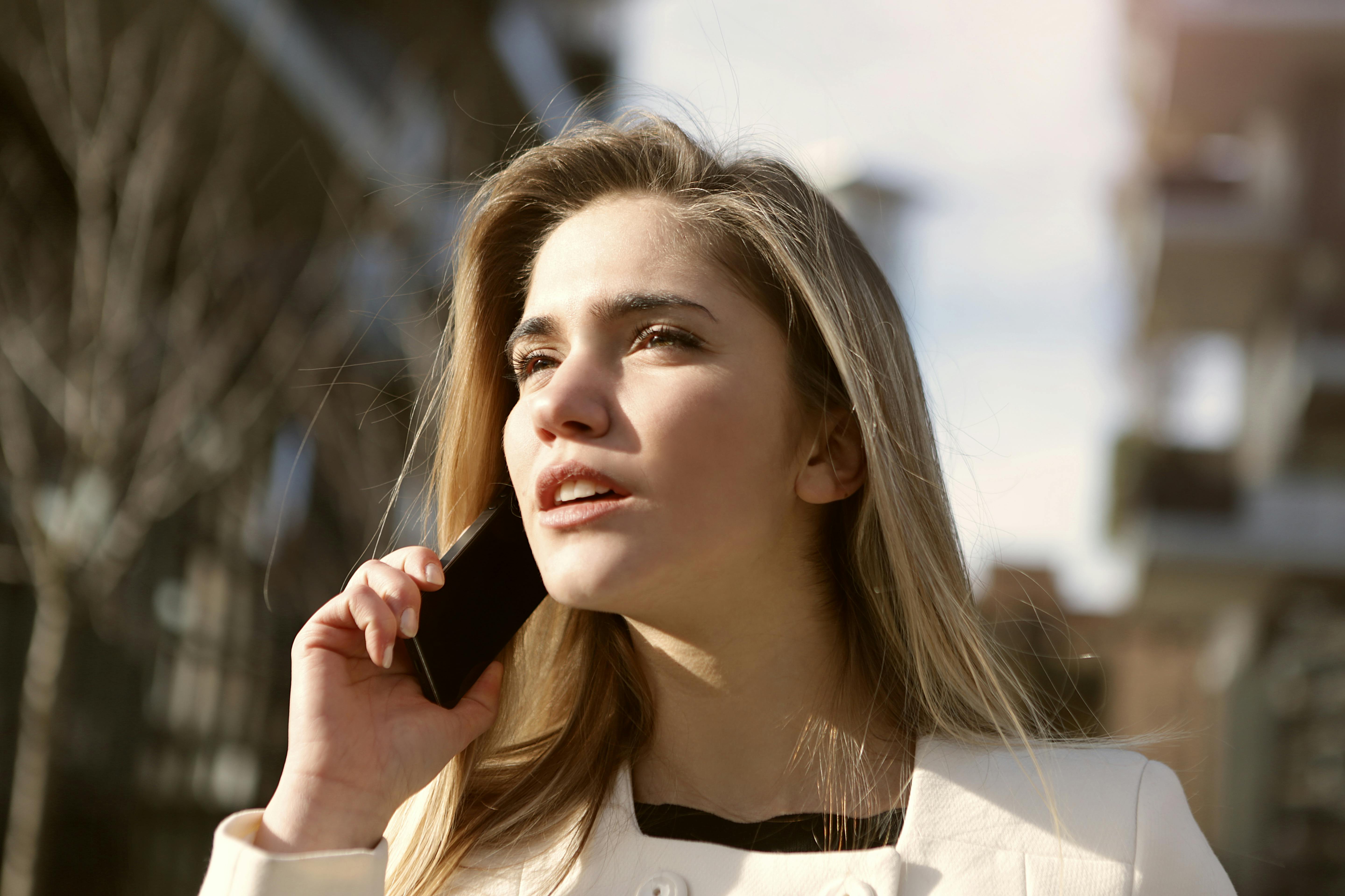 Mujer habla por teléfono al aire libre | Fuente: Pexels