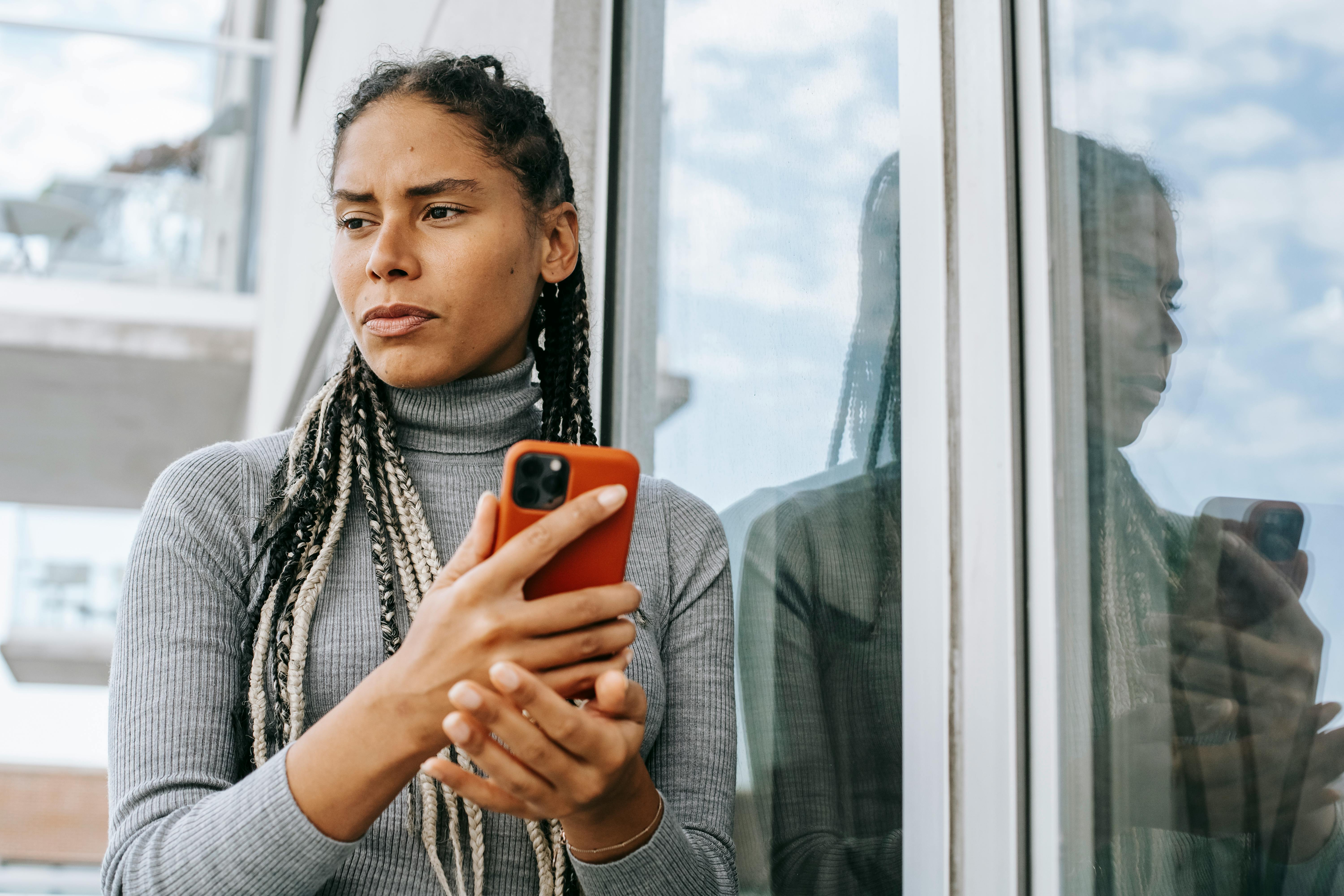 Mujer mirando a un lado con el teléfono en la mano | Foto: Pexels