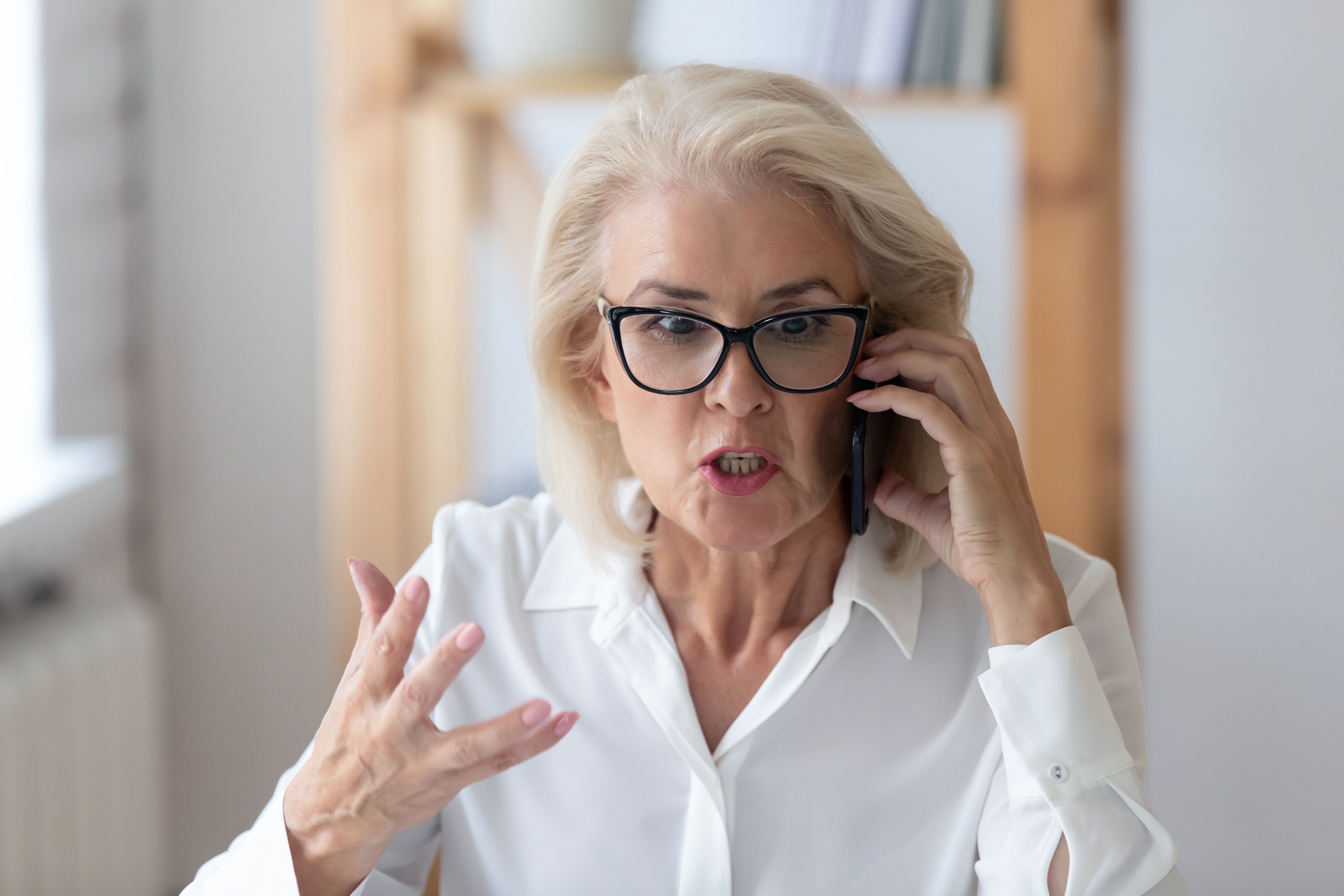 Mujer mayor disgustada hablando por teléfono | Fuente: Shutterstock