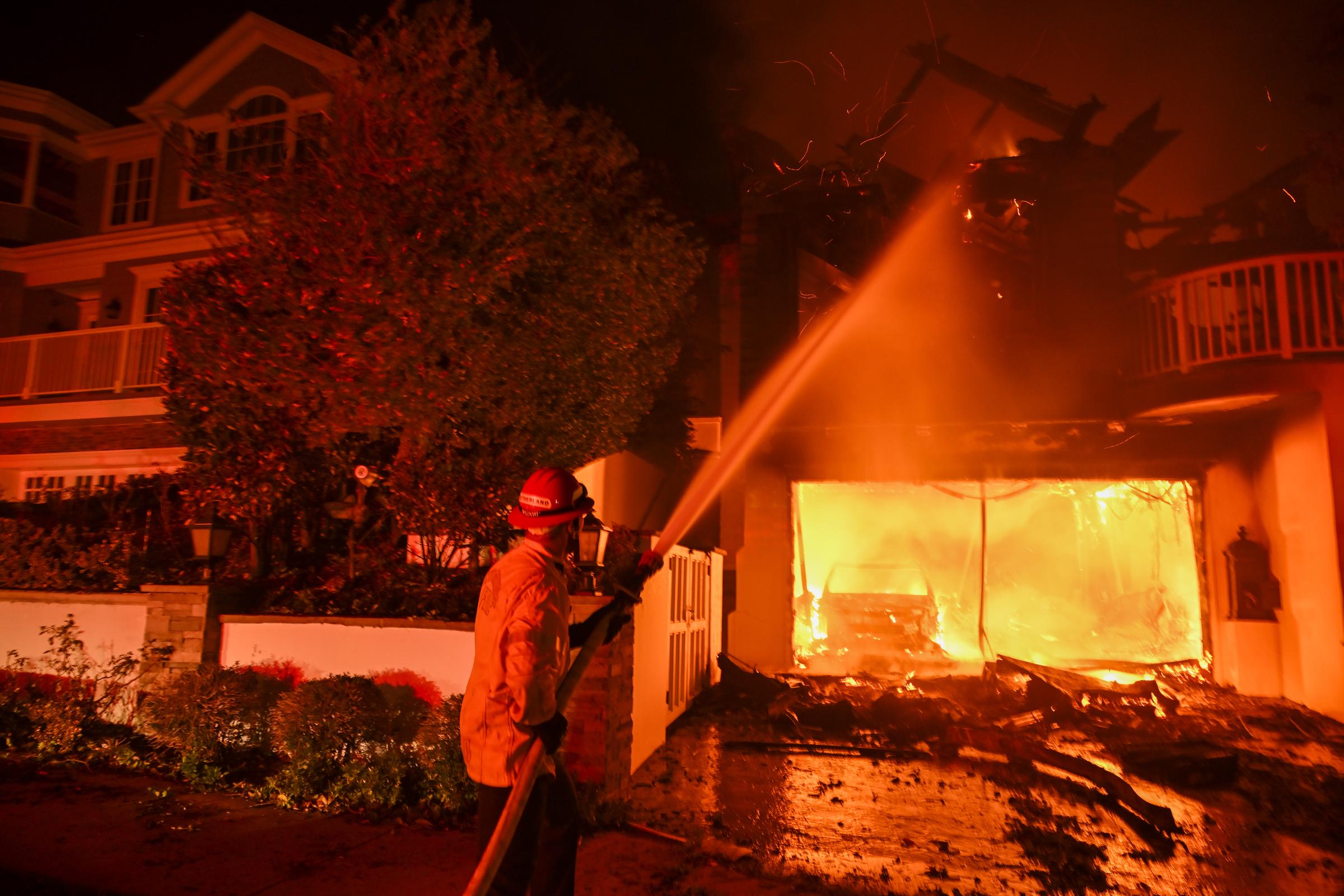 Un bombero rocía una casa incendiada en Pacific Palisades, California, el 8 de enero de 2025. | Fuente: Getty Images