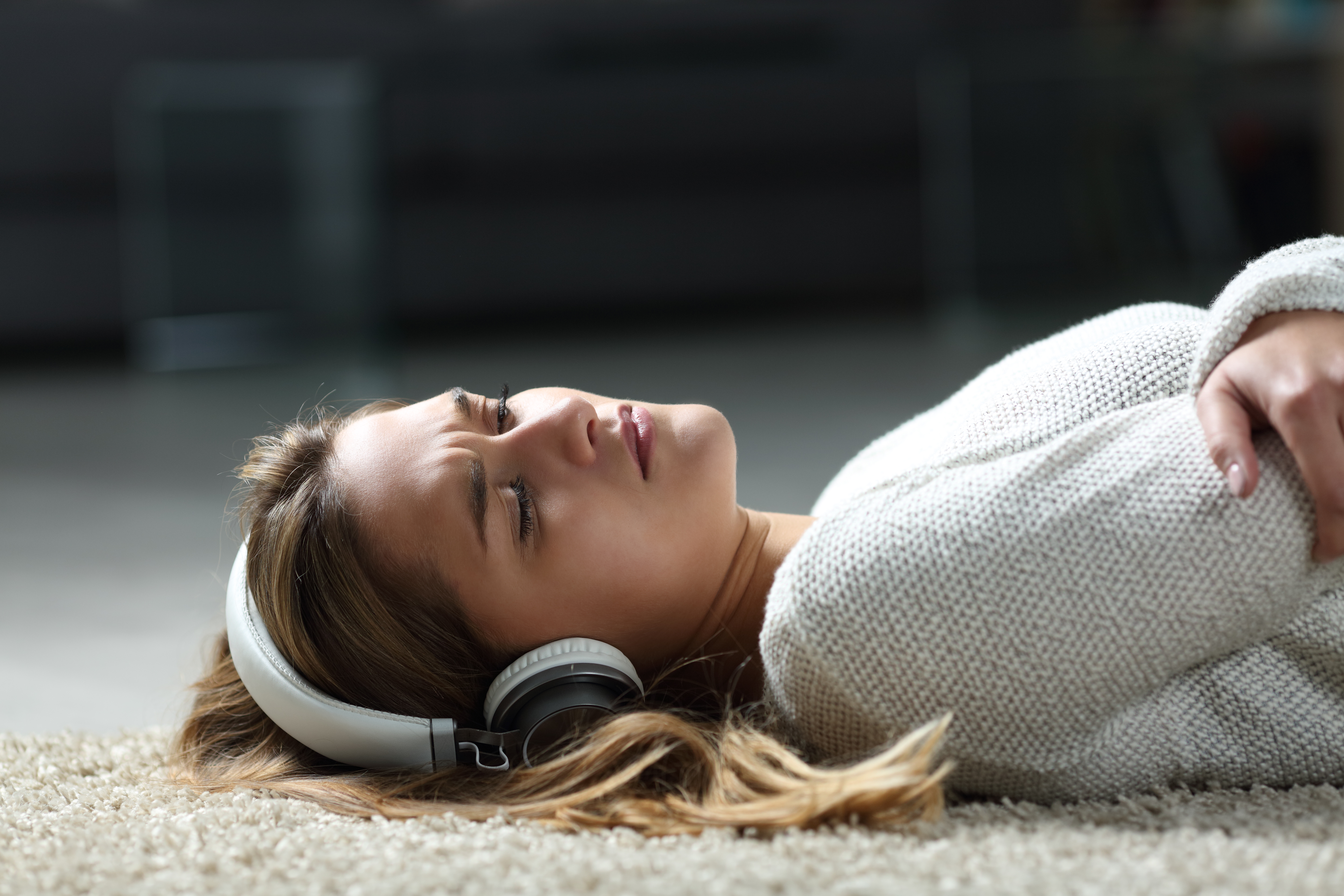 Mujer triste escuchando música en el suelo | Foto: Getty Images