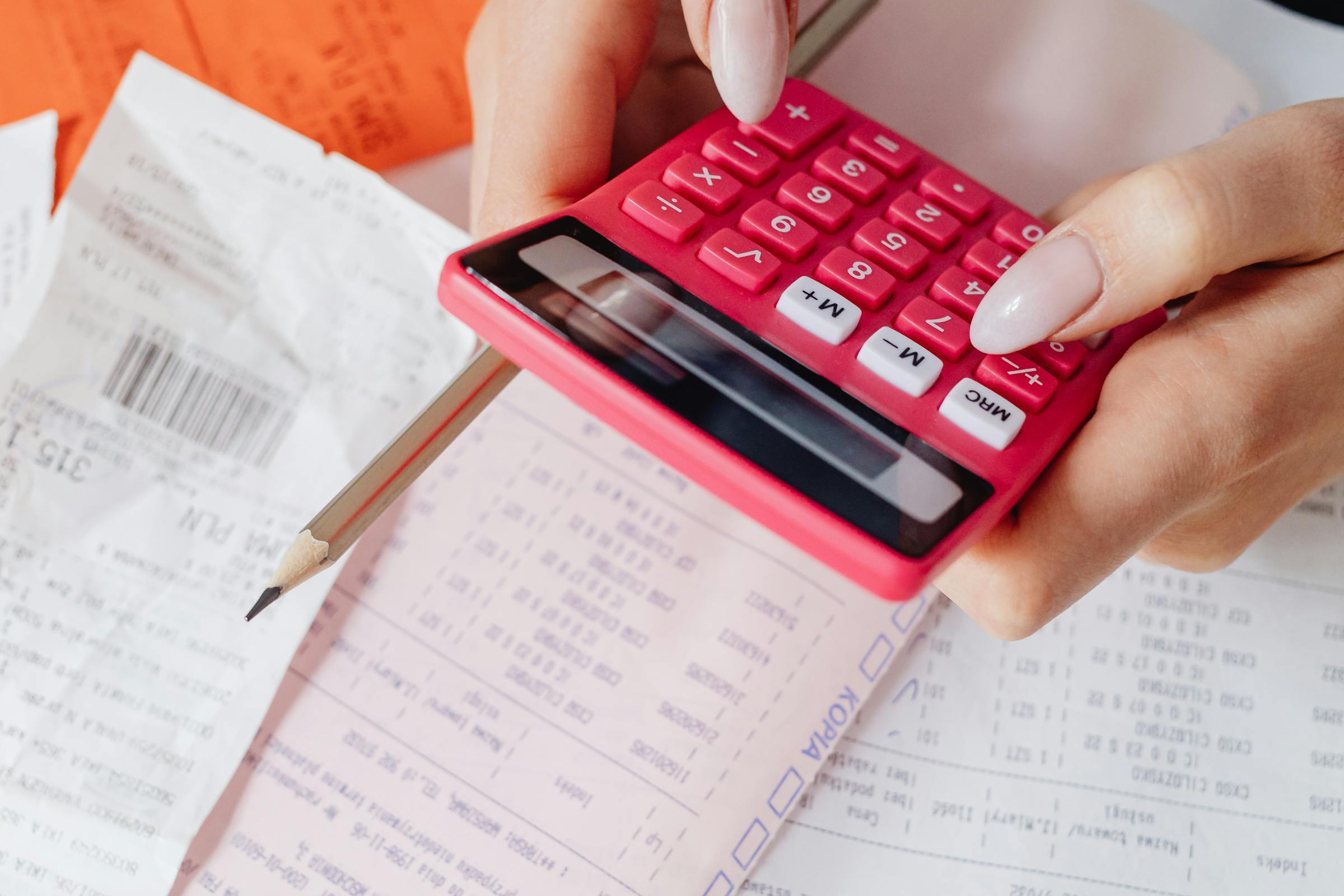 Una mujer usando una calculadora mientras gestiona facturas | Fuente: Pexels