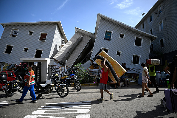 Un hombre transporta un colchón junto a edificios residenciales dañados tras el terremoto ocurrido en Catia La Mar, estado La Guaira, a unos 30 kilómetros al noroeste de Caracas, el 25 de junio de 2026.