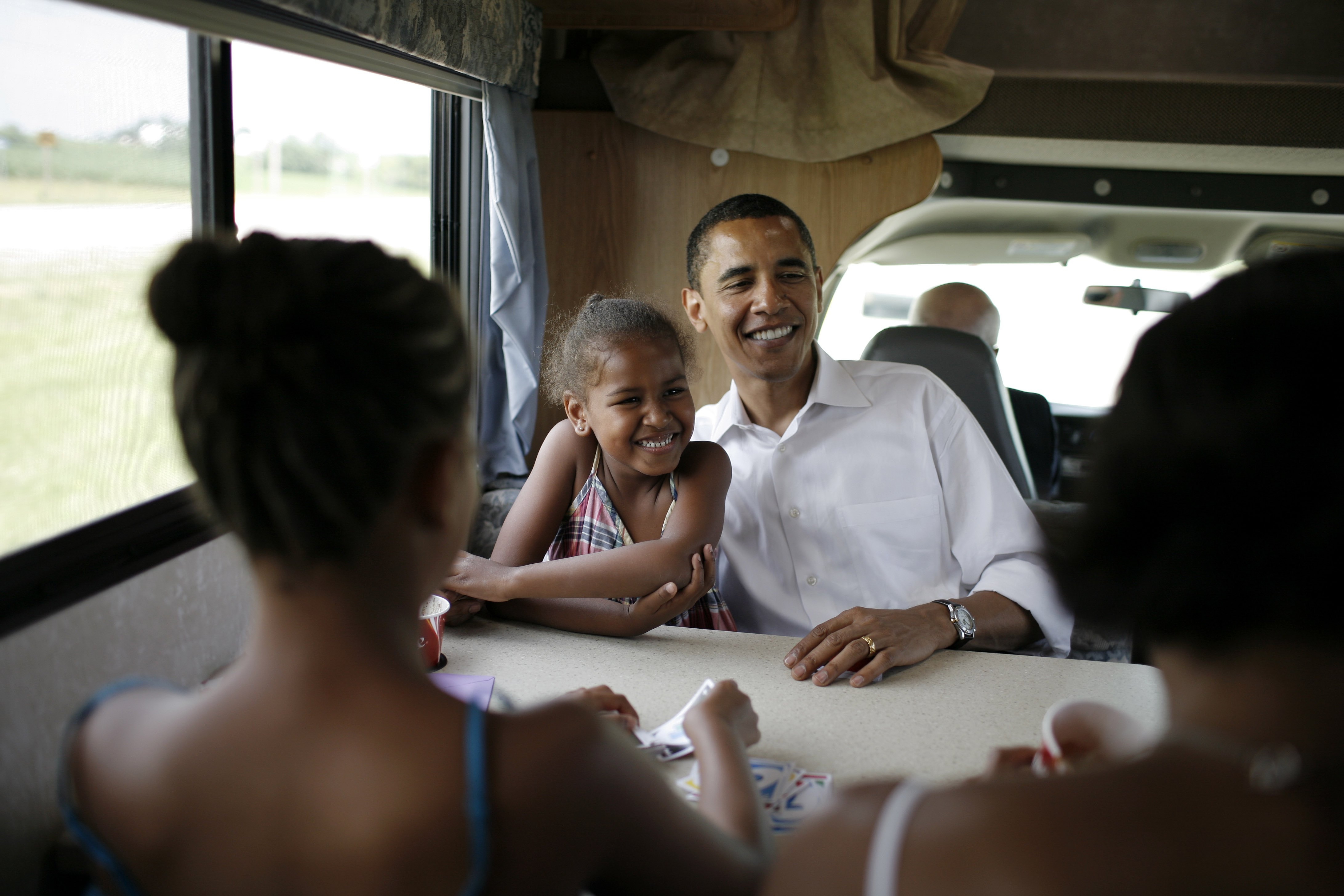 Michelle, Malia, Sasha y Barack Obama juegan a las cartas en su autocaravana mientras hacen campaña entre Oskaloosa y Pella, Iowa, el 4 de julio de 2007 | Fuente: Getty Images