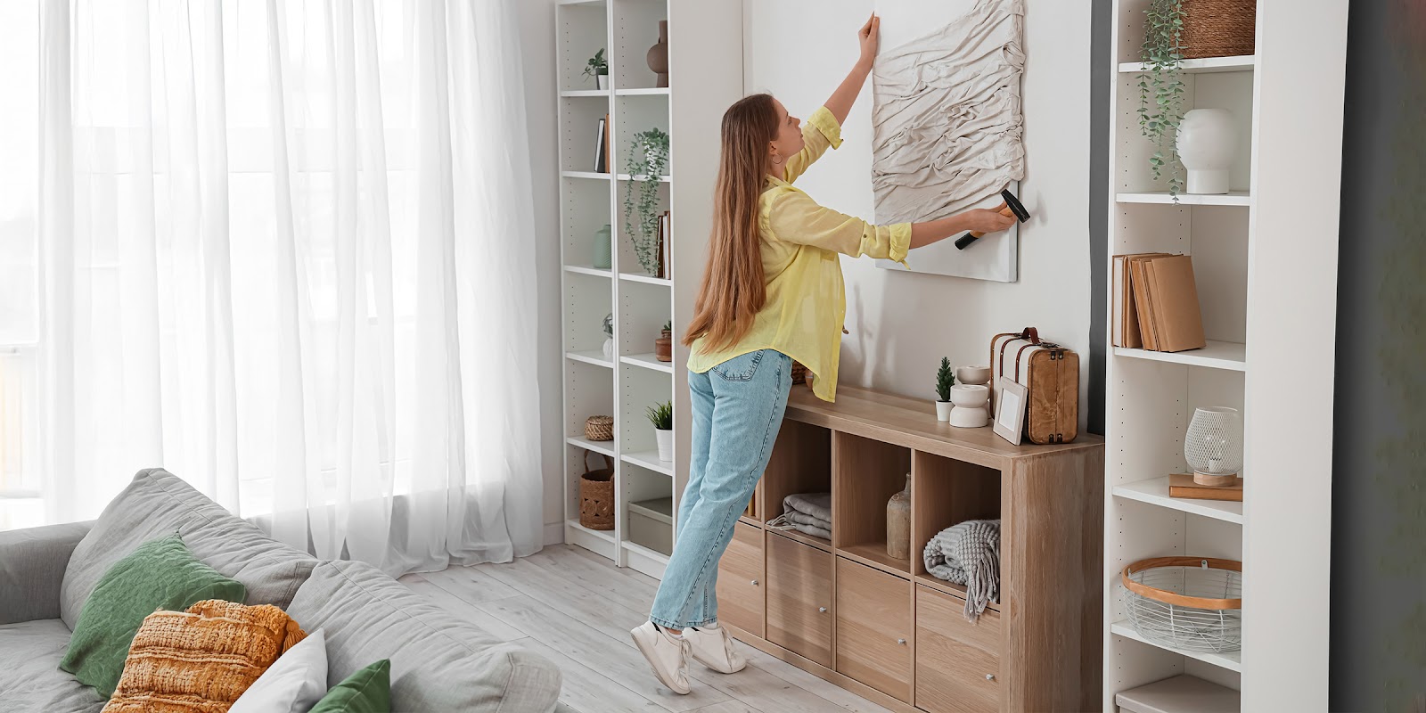 Una donna che appende un quadro | Fonte: Shutterstock