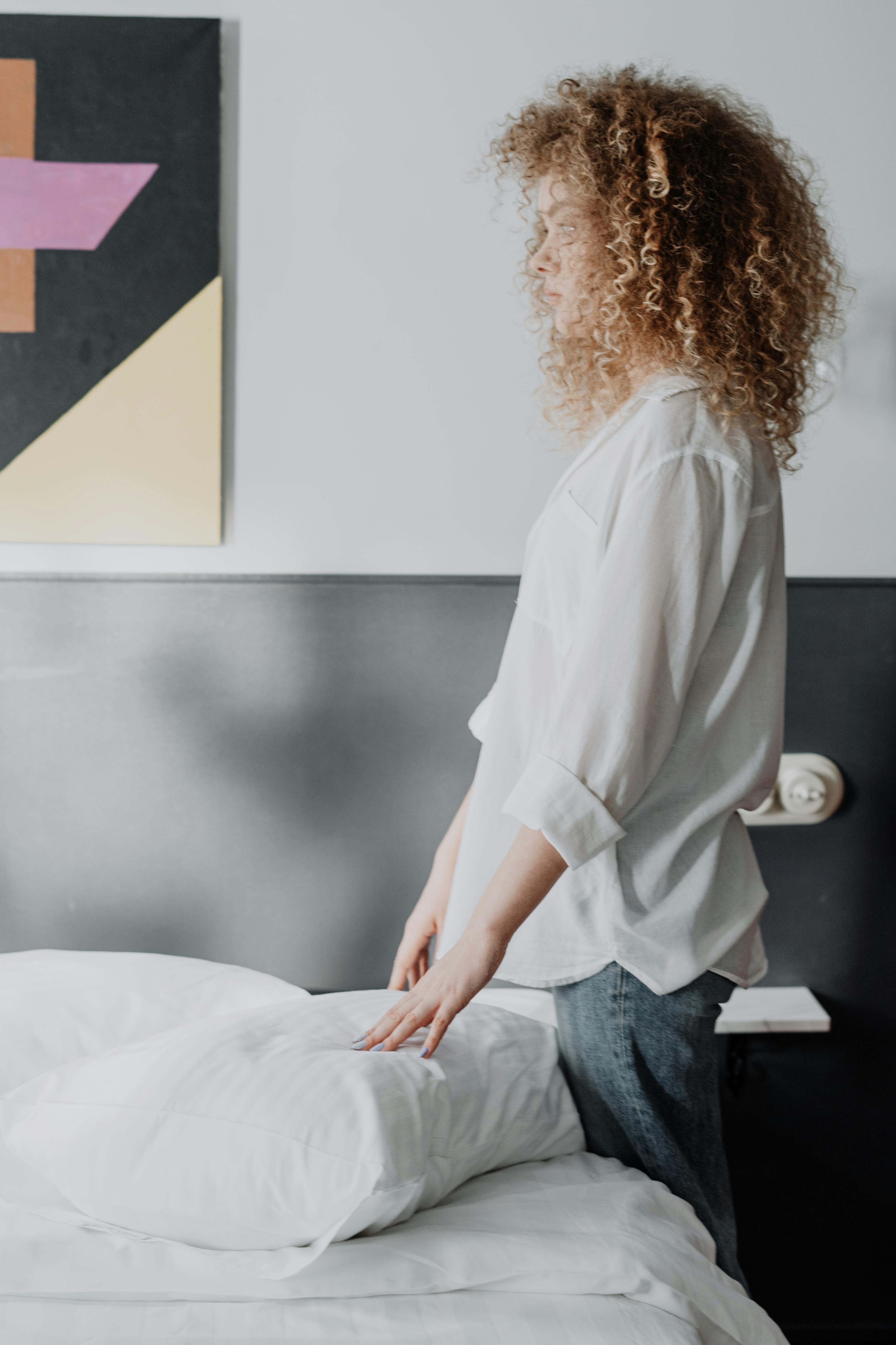 Una mujer de pie junto a una cama | Foto: Pexels