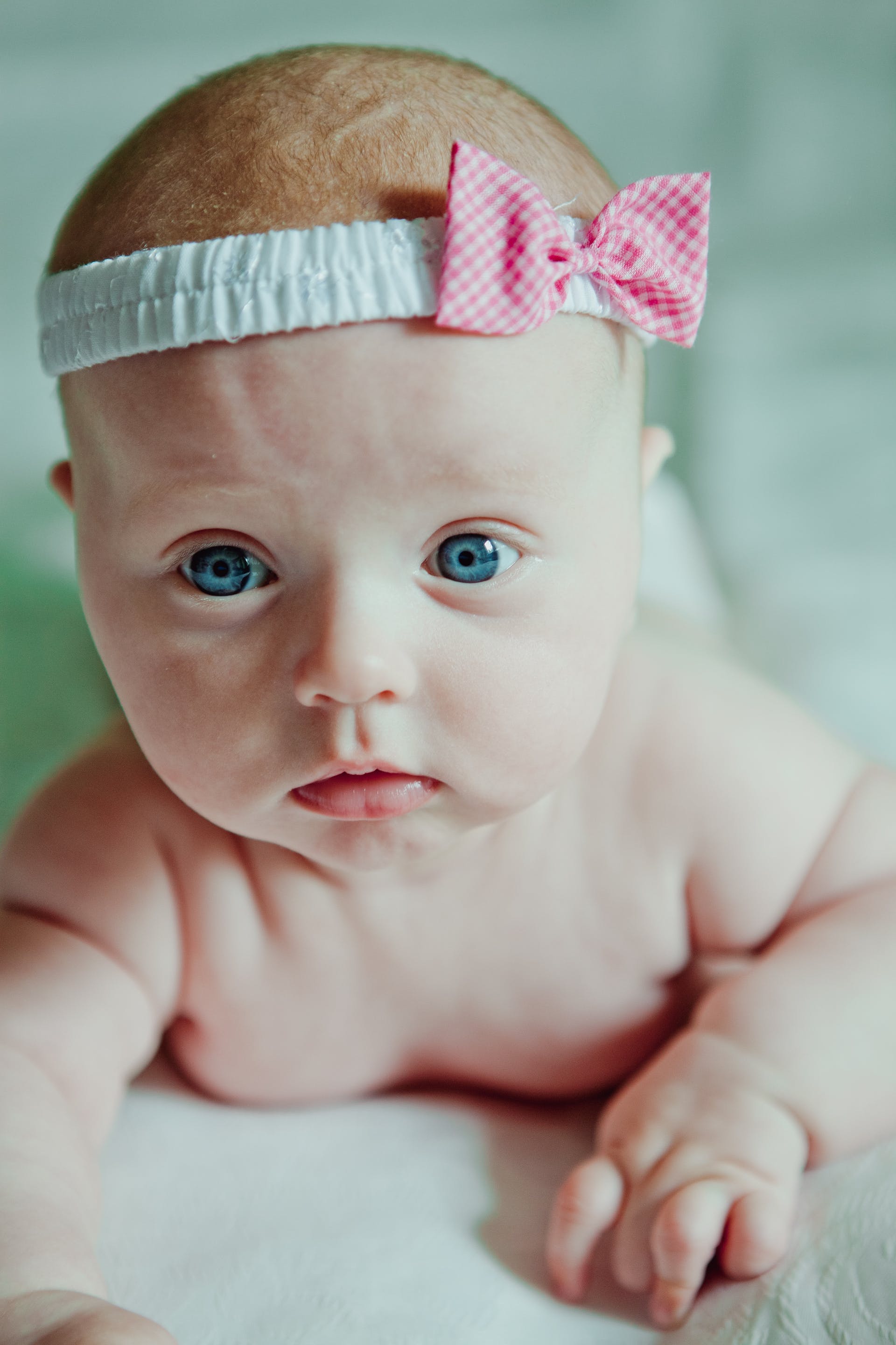 Primer plano de un recién nacido con ojos azules y diadema | Foto: Pexels