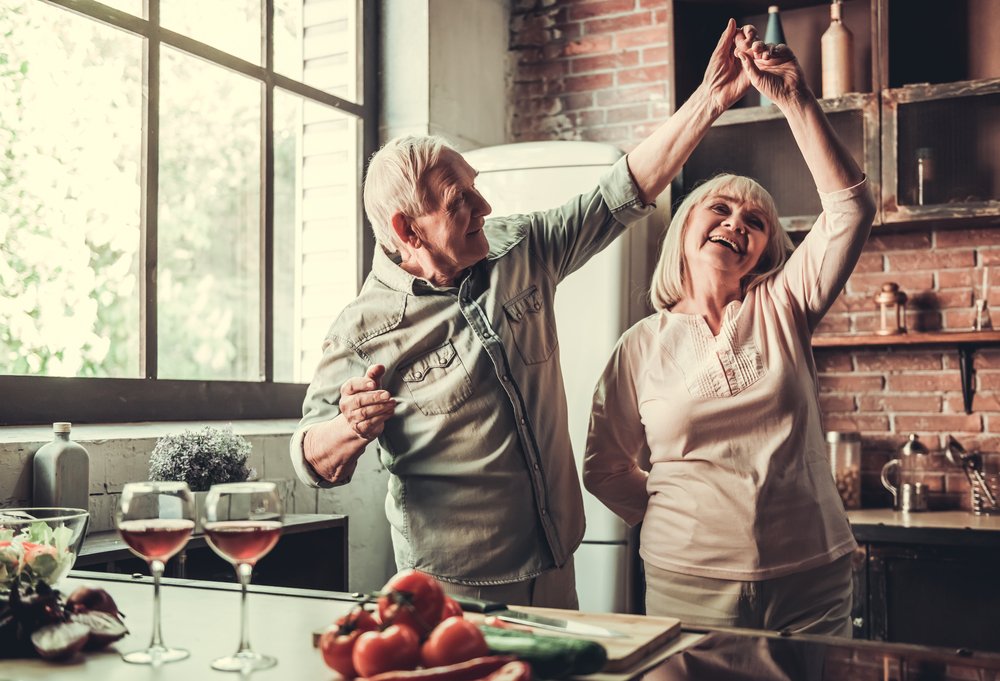 Pareja de ancianos bailando y sonriendo mientras cocinan juntos. I Foto: Shutterstock.