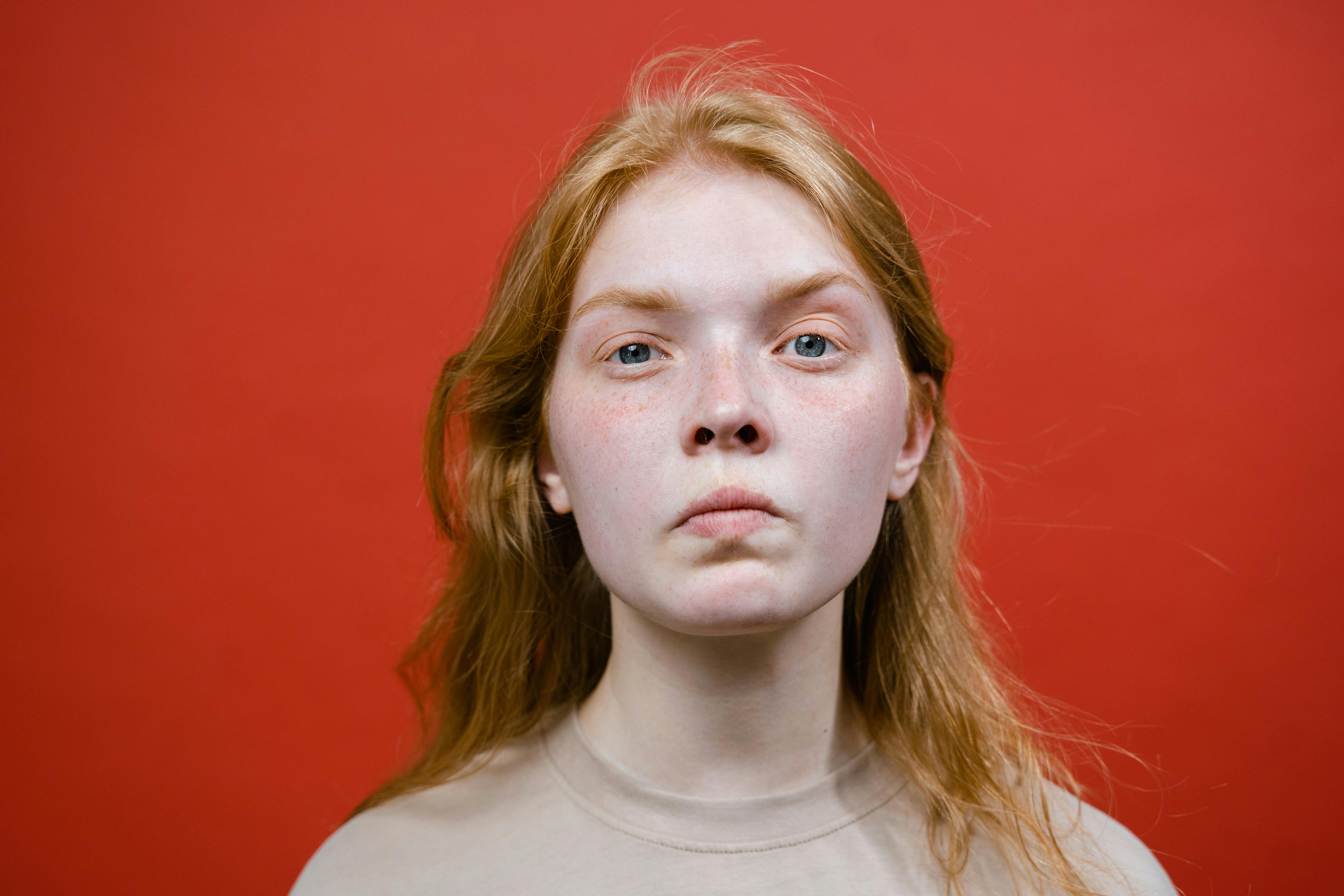 Una ragazza arrabbiata su uno sfondo rosso | Fonte: Pexels