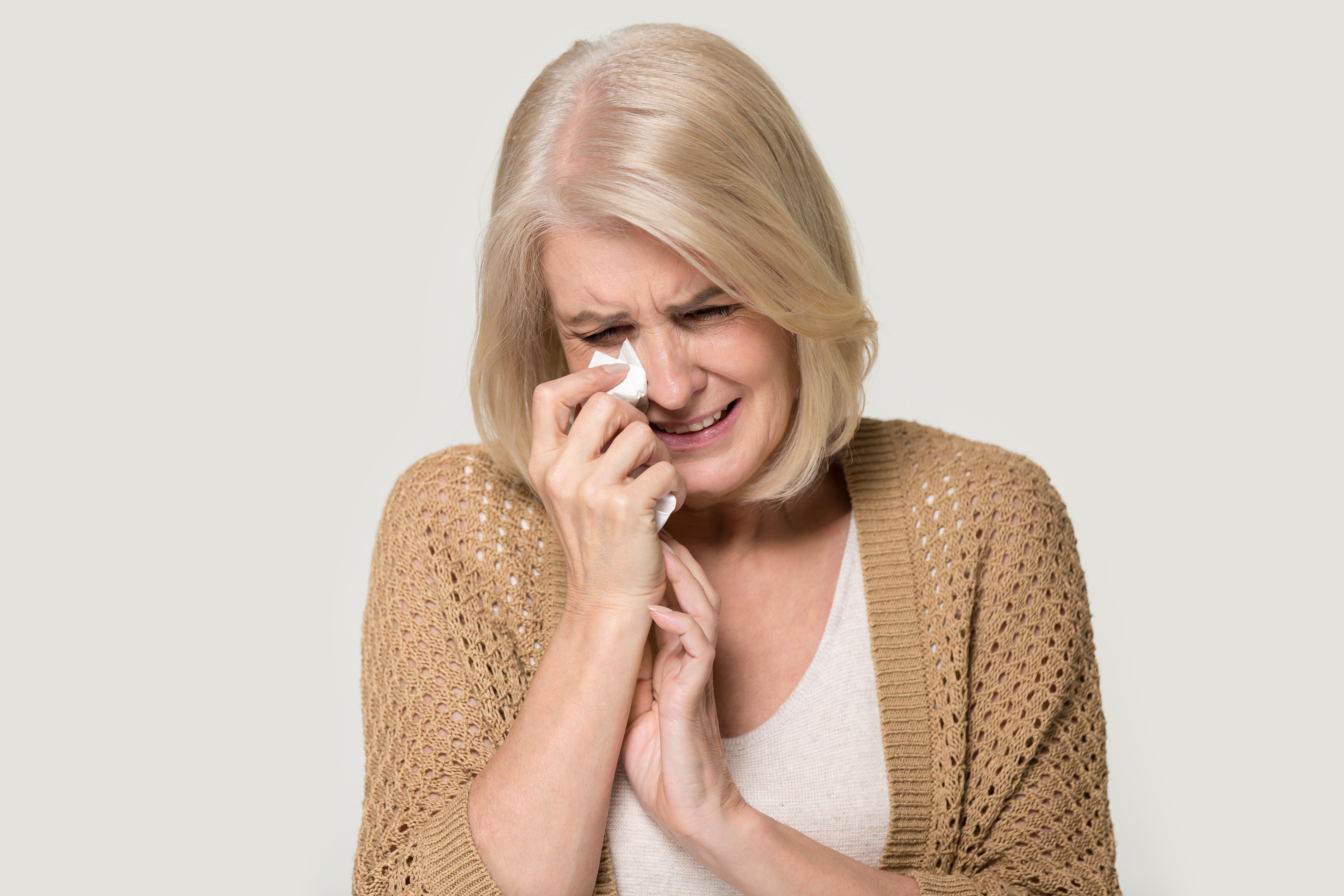 Una señora mayor llorando secándose las lágrimas con el pañuelo | Fuente: Shutterstock