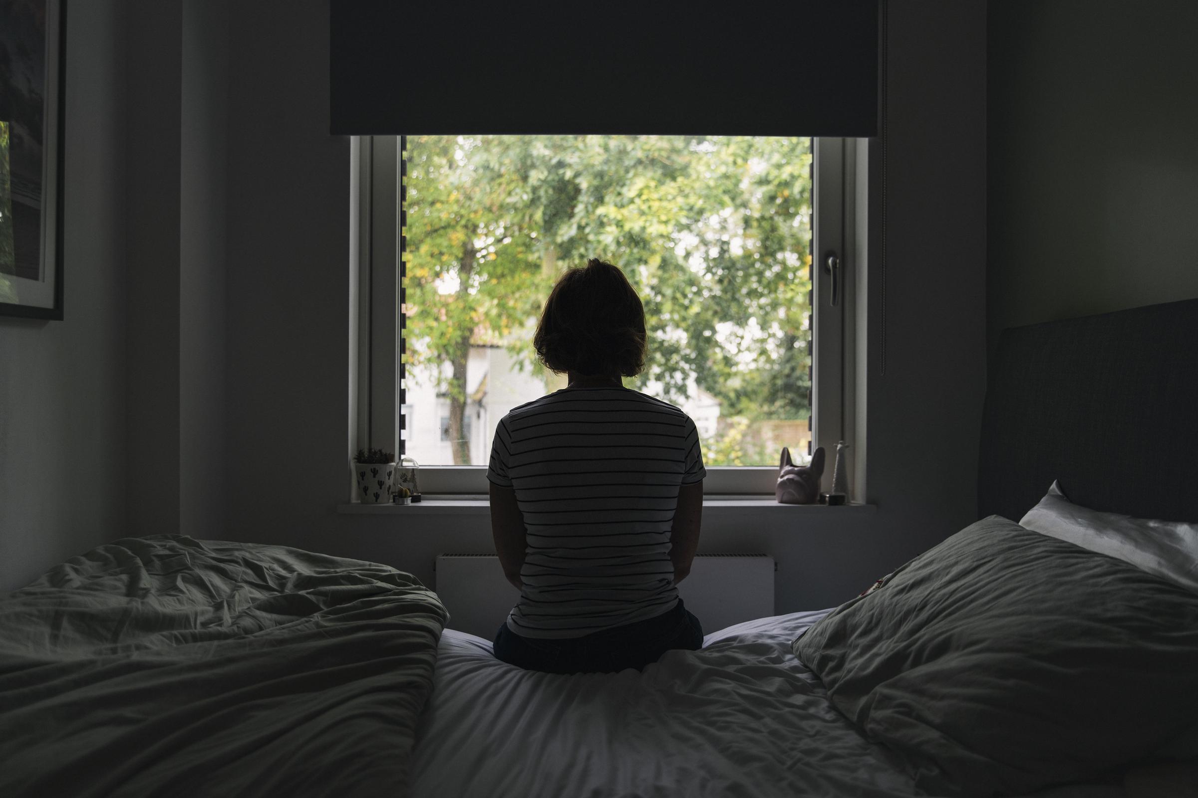 Una mujer mirando por la ventana de su habitación | Fuente: Getty Images