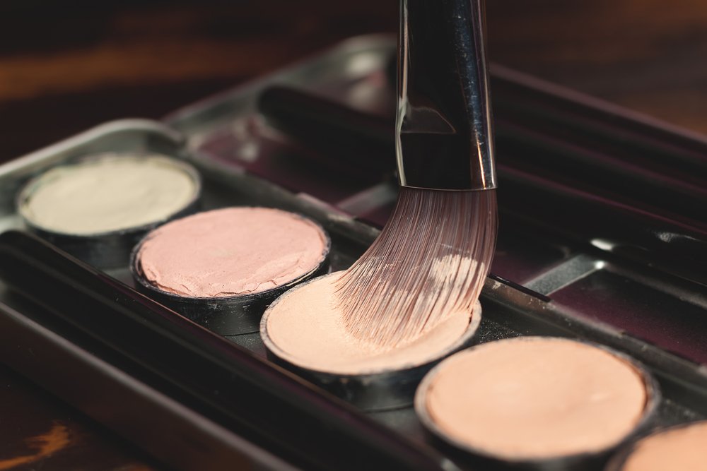 Brocha de maquillaje y paleta de correctores de varios colores. | Foto: Shutterstock