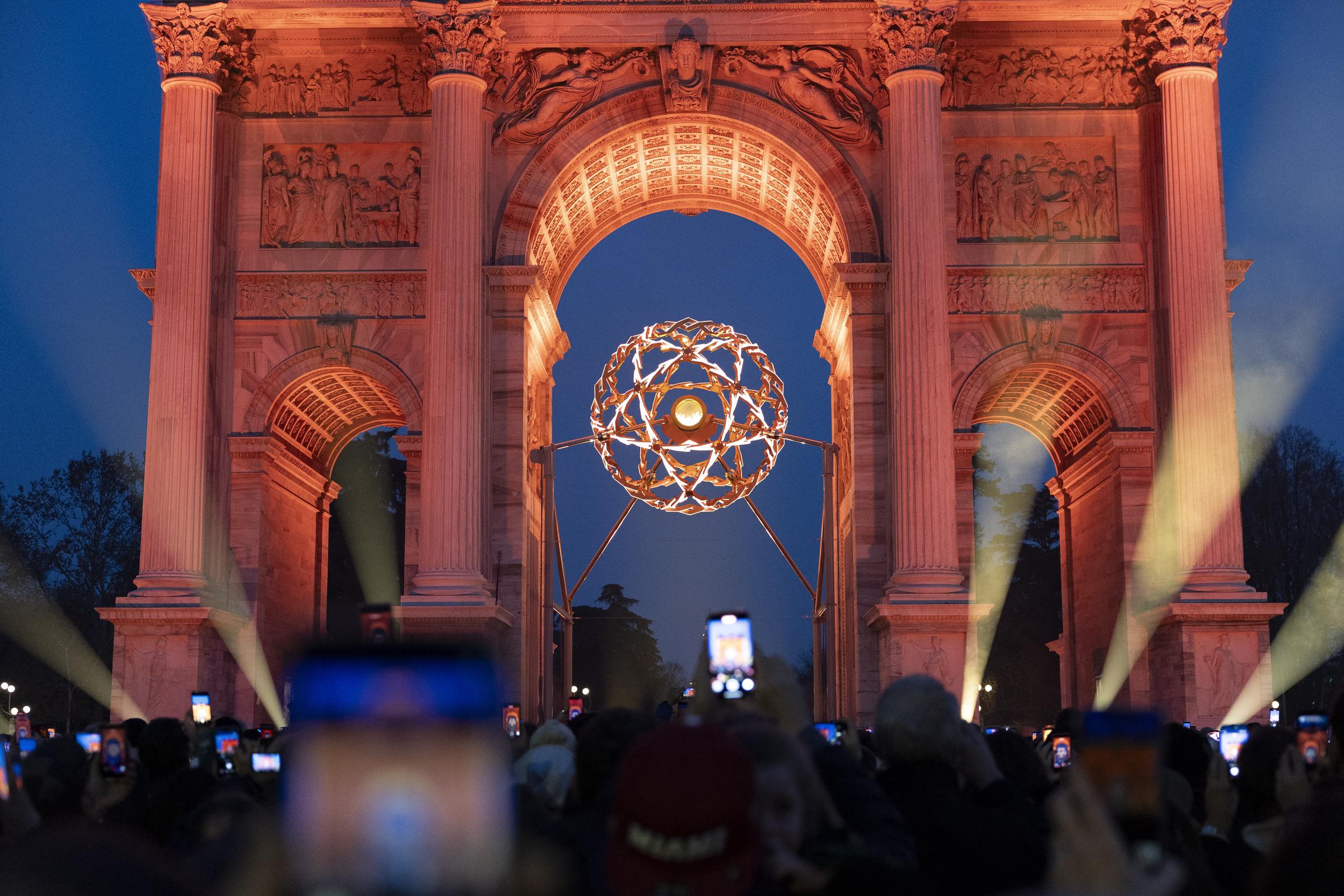 Los visitantes toman fotografías del pebetero olímpico durante el espectáculo tras el atardecer del 8 de febrero de 2026 en Milán, Italia. | Fuente: Getty Images