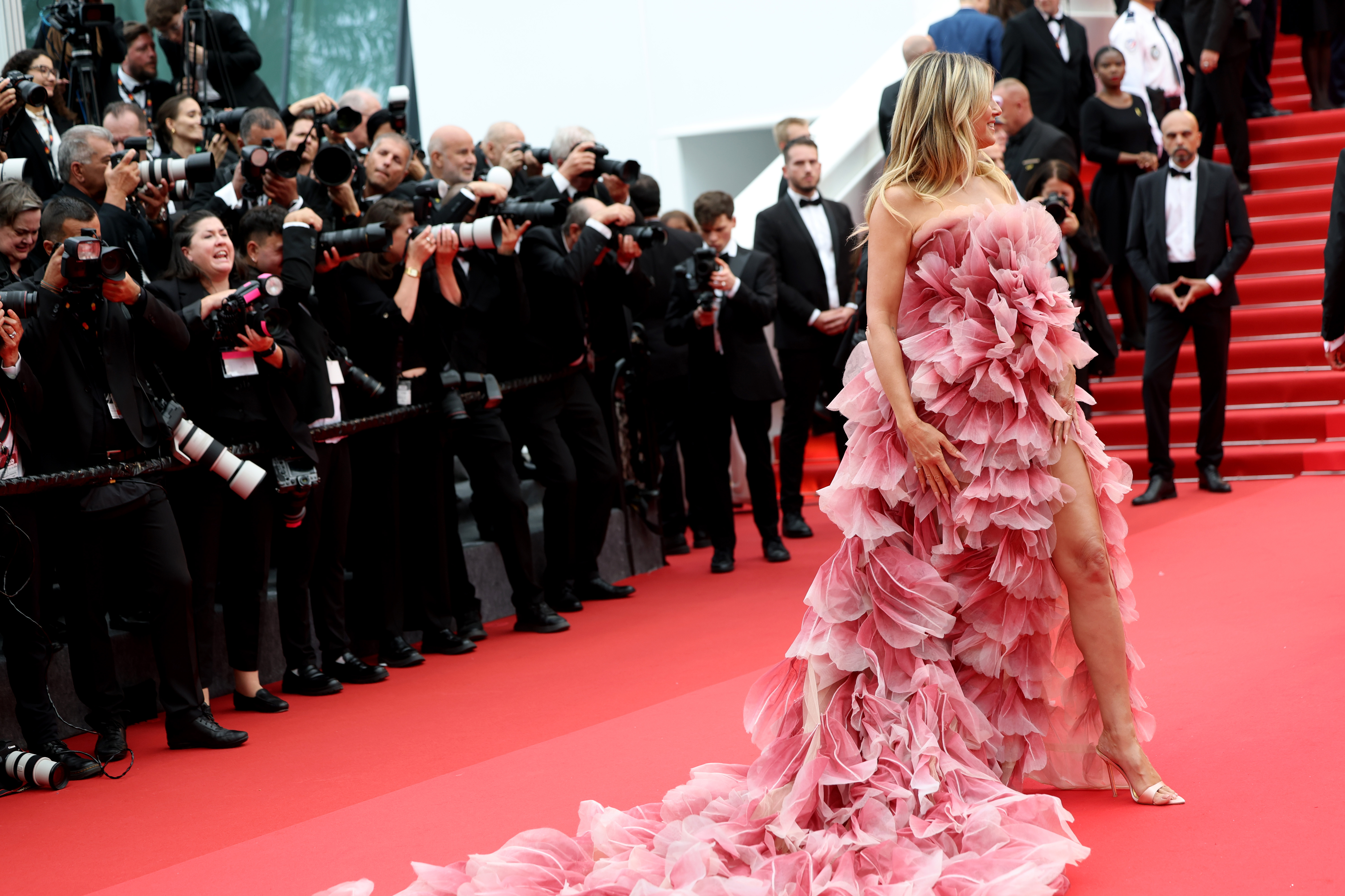 Un primer plano revela la intrincada belleza del vestido de Klum: cada capa de volantes imita delicados pétalos, que brillan suavemente en tonos rosas. La artesanía es exquisita y confiere al vestido un aire romántico, casi etéreo.