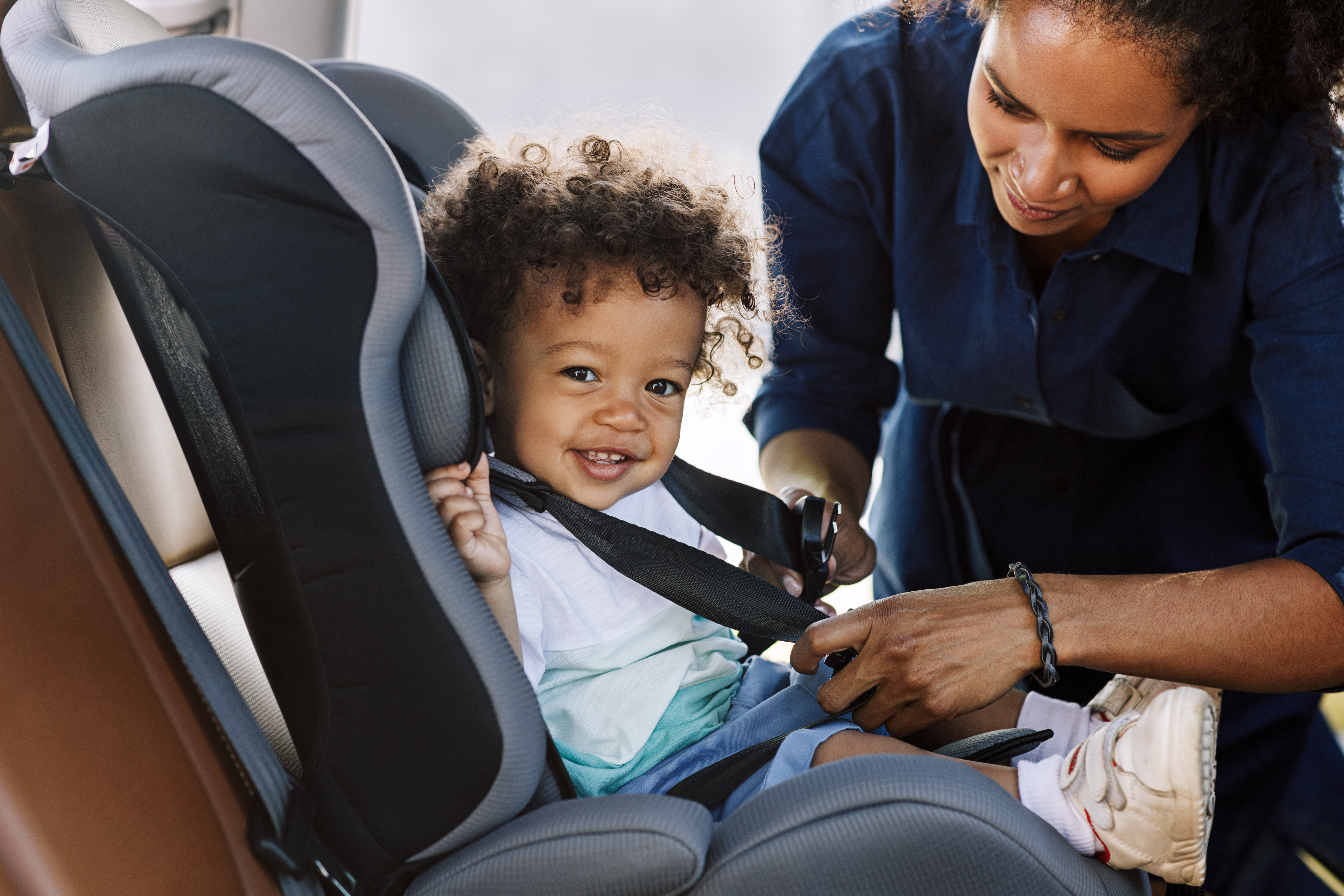 Madre atando a su hijo a un asiento de coche | Foto: Shutterstock