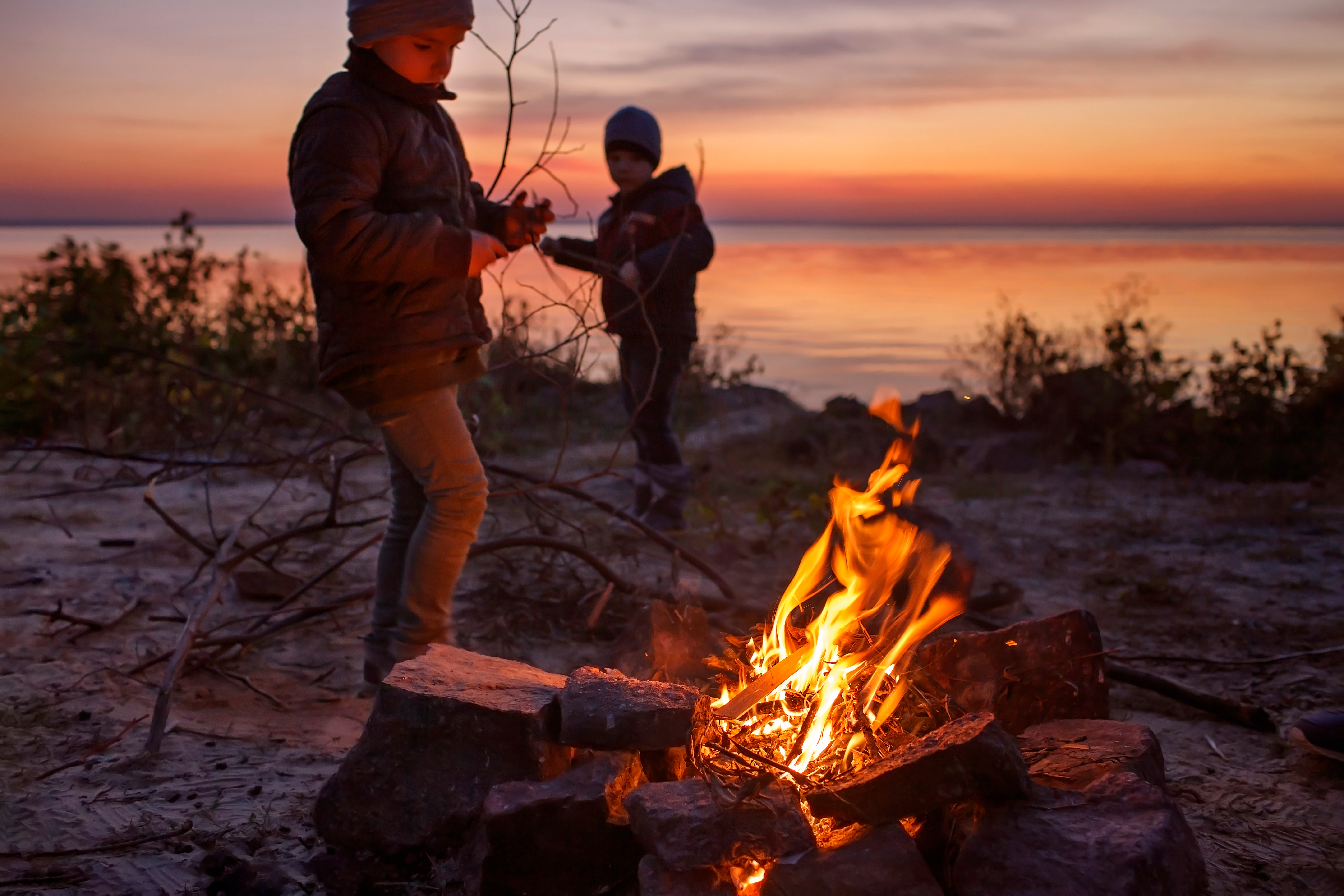 Niños de diferentes edades sentados cerca del fuego | Fuente: Shutterstock.com