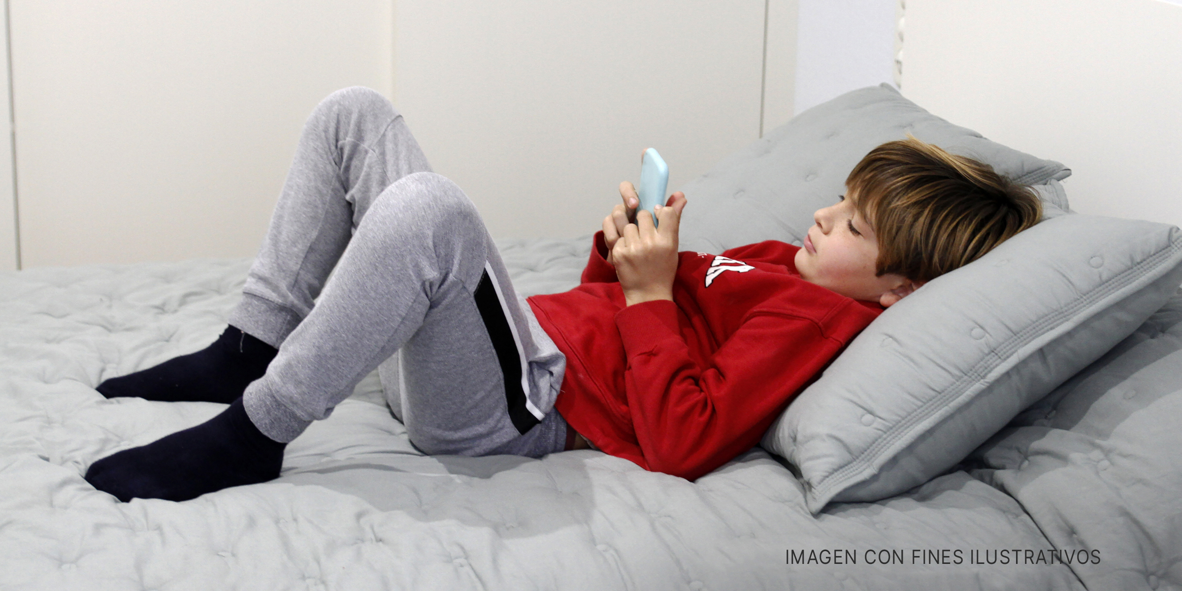 Chico usando su teléfono en un sofá. | Foto: Getty Images