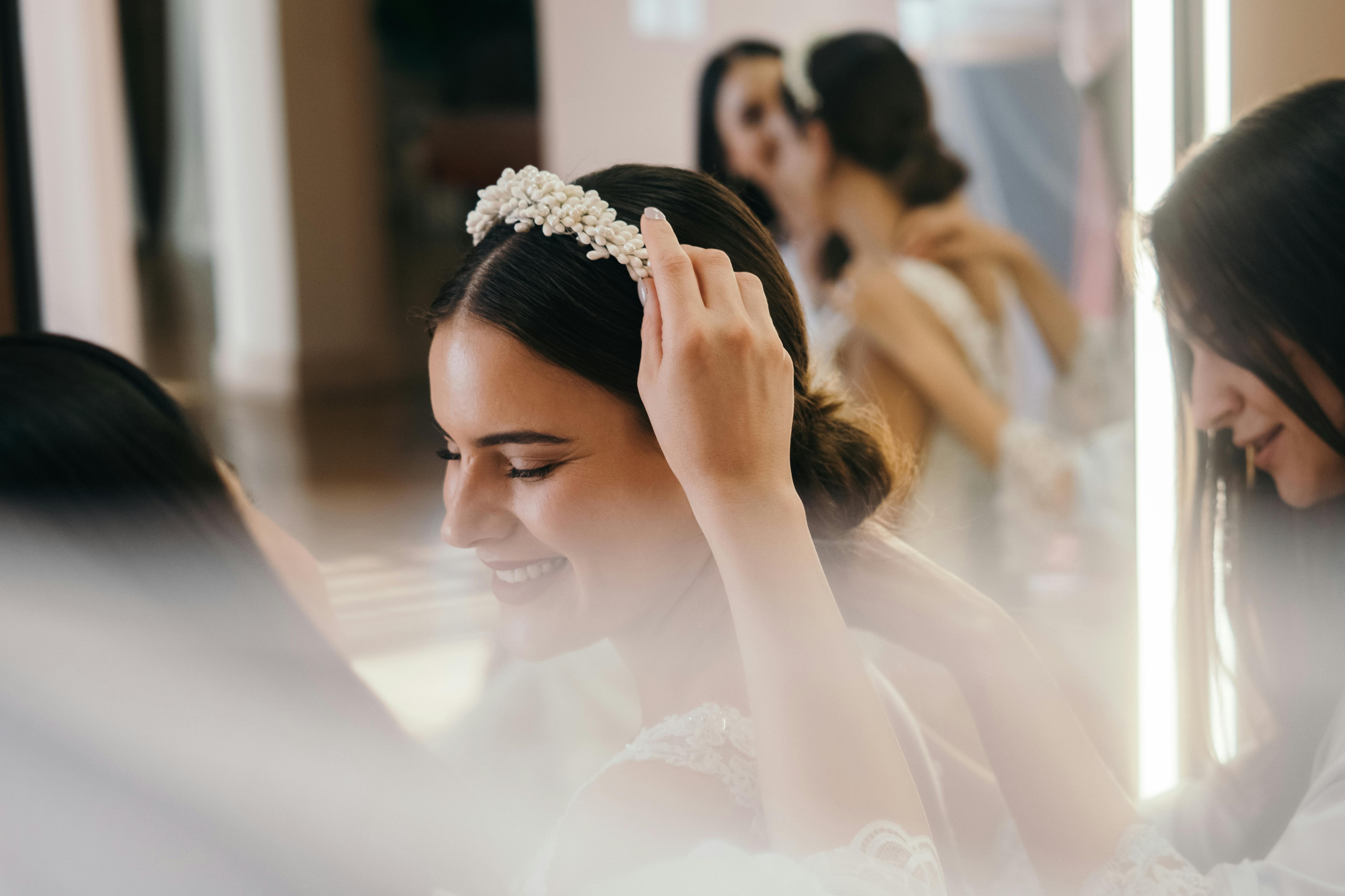 Una dama de honor colocando una diadema en la cabeza de la novia | Fuente: Pexels