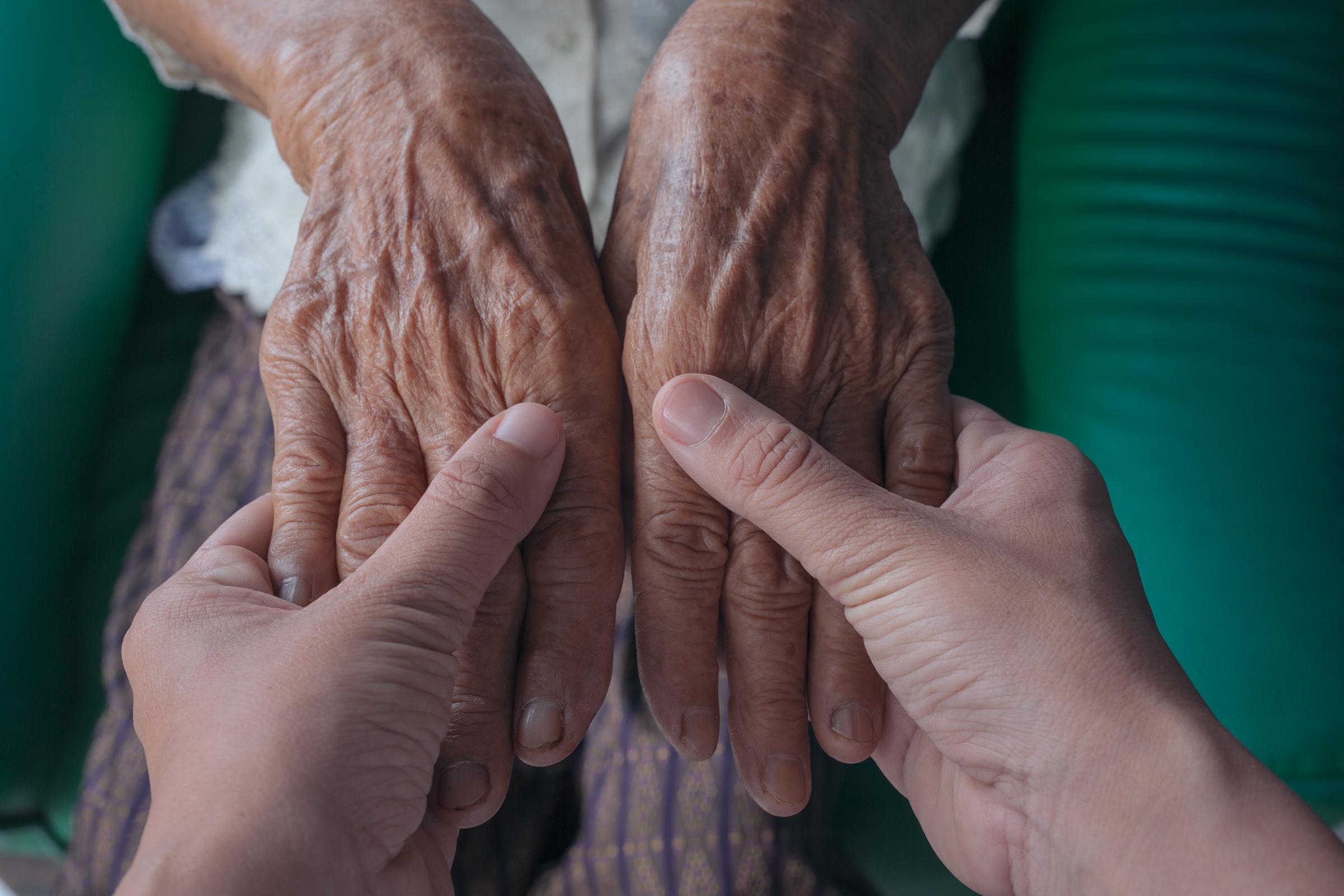 Primer plano de un joven cogiendo la mano de su abuela | Fuente: Freepik