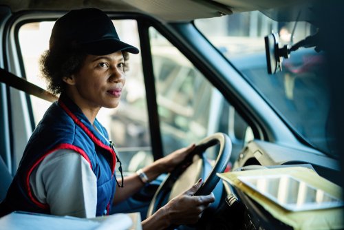 Mujer del Servicio Postal conduciendo un carro. | Foto: Shutterstock