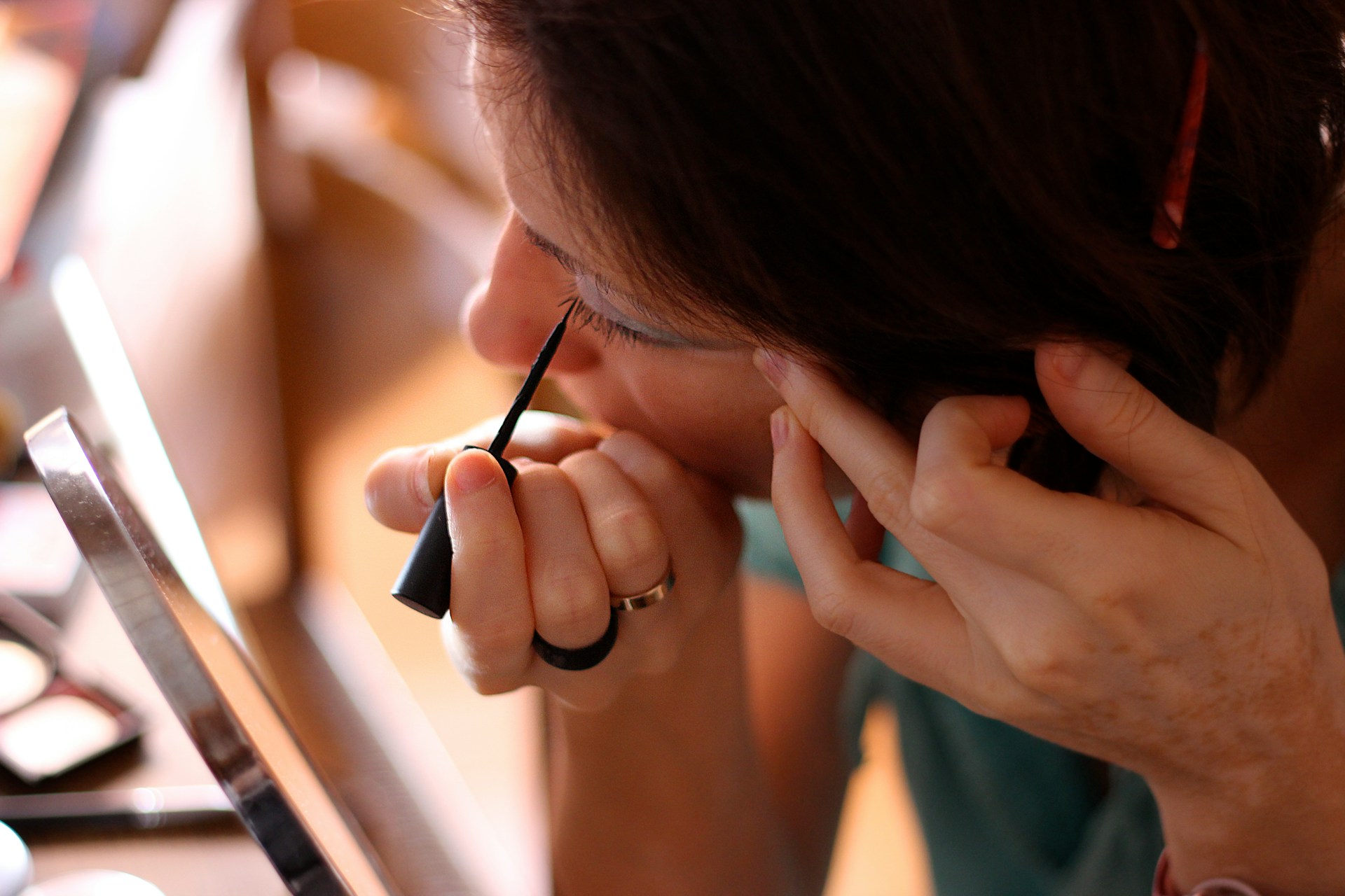 Una mujer mirándose al espejo y aplicándose delineador de ojos | Fuente: Unsplash