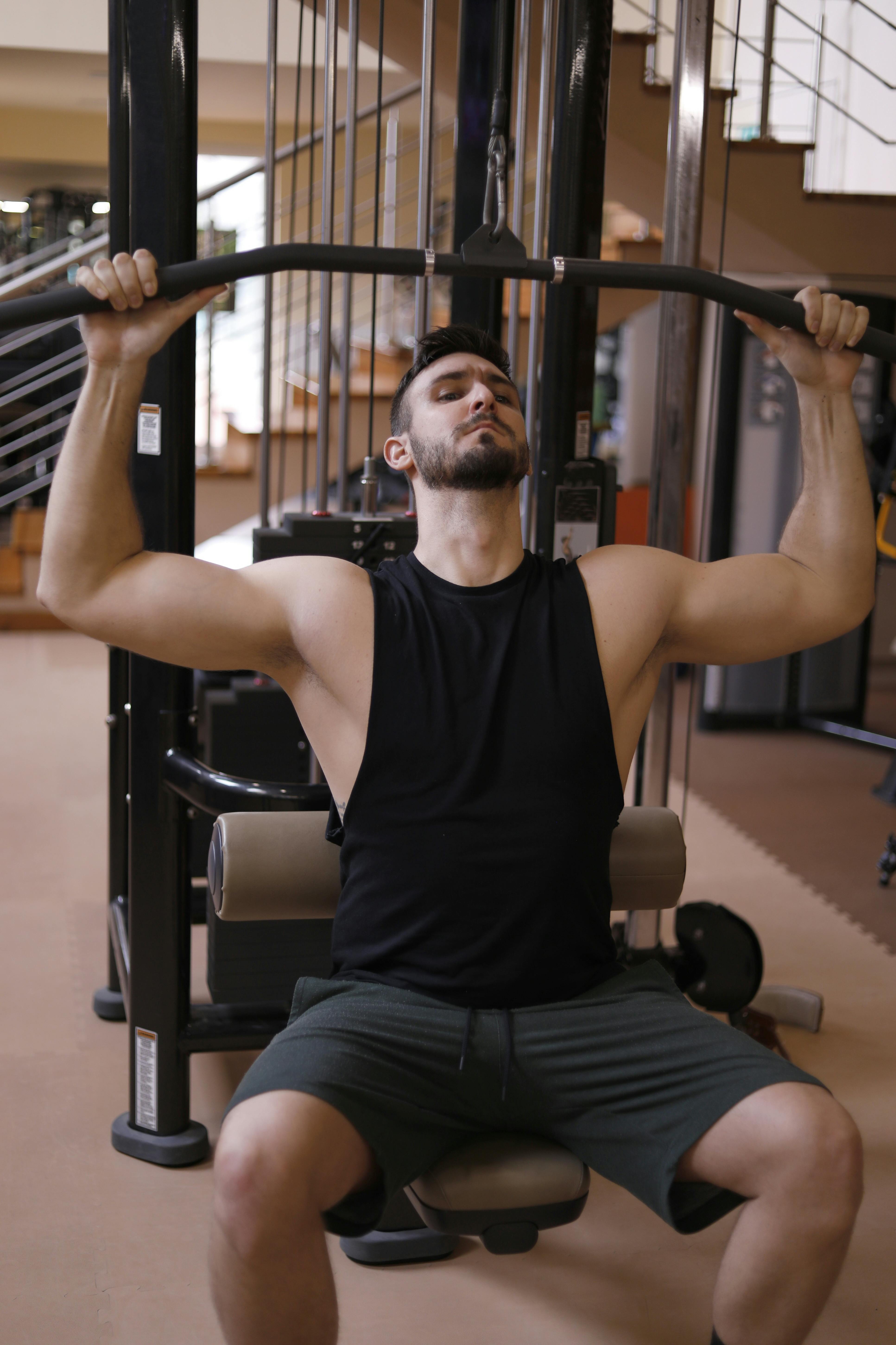 Un hombre con camiseta de tirantes negra haciendo ejercicio | Fuente: Pexels