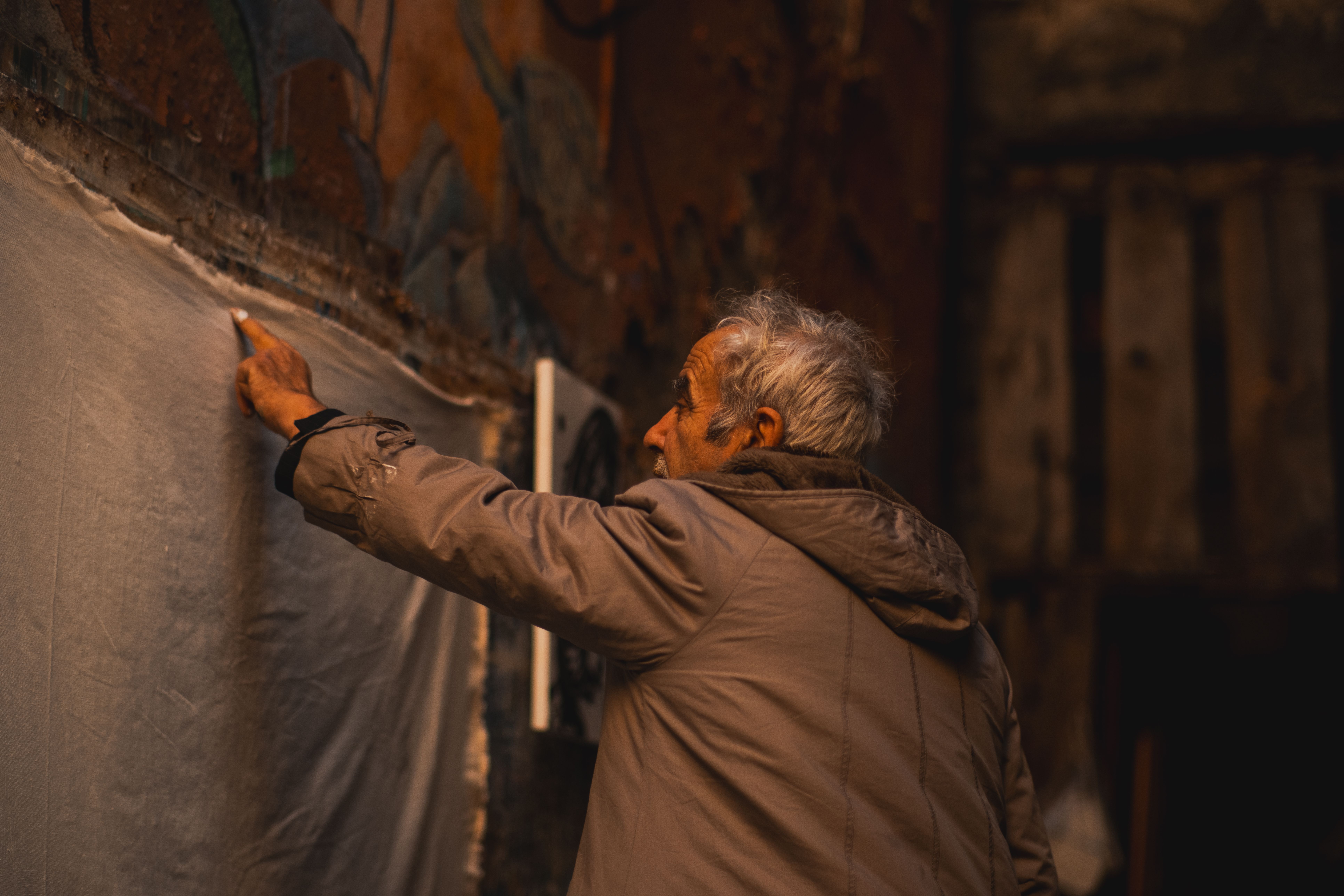 Abuelo escribiendo en una pared | Fuente: Pexels