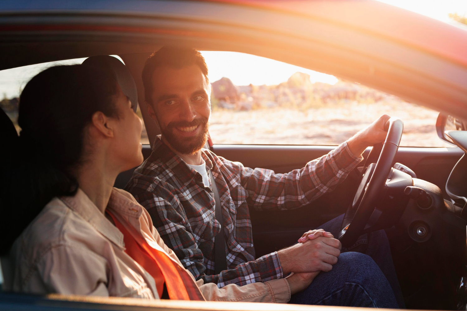 Un hombre encantado mirando a su pareja y sonriendo en su automóvil | Fuente: Freepik