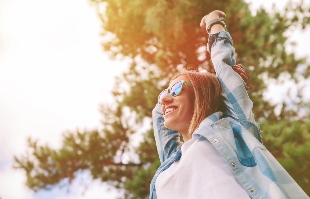 Mujer feliz con lentes de sol al aire libre. Fuente: Shutterstock