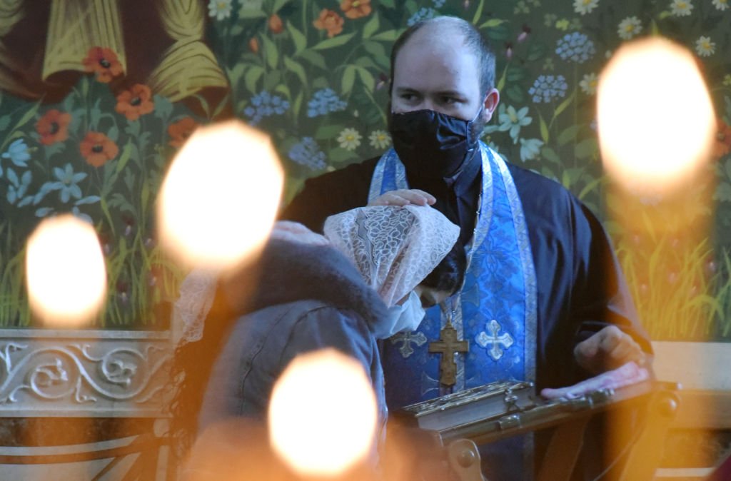Sacerdote ruso se protege con una mascarilla mientras confiesa a un creyente. | Foto: Getty Images