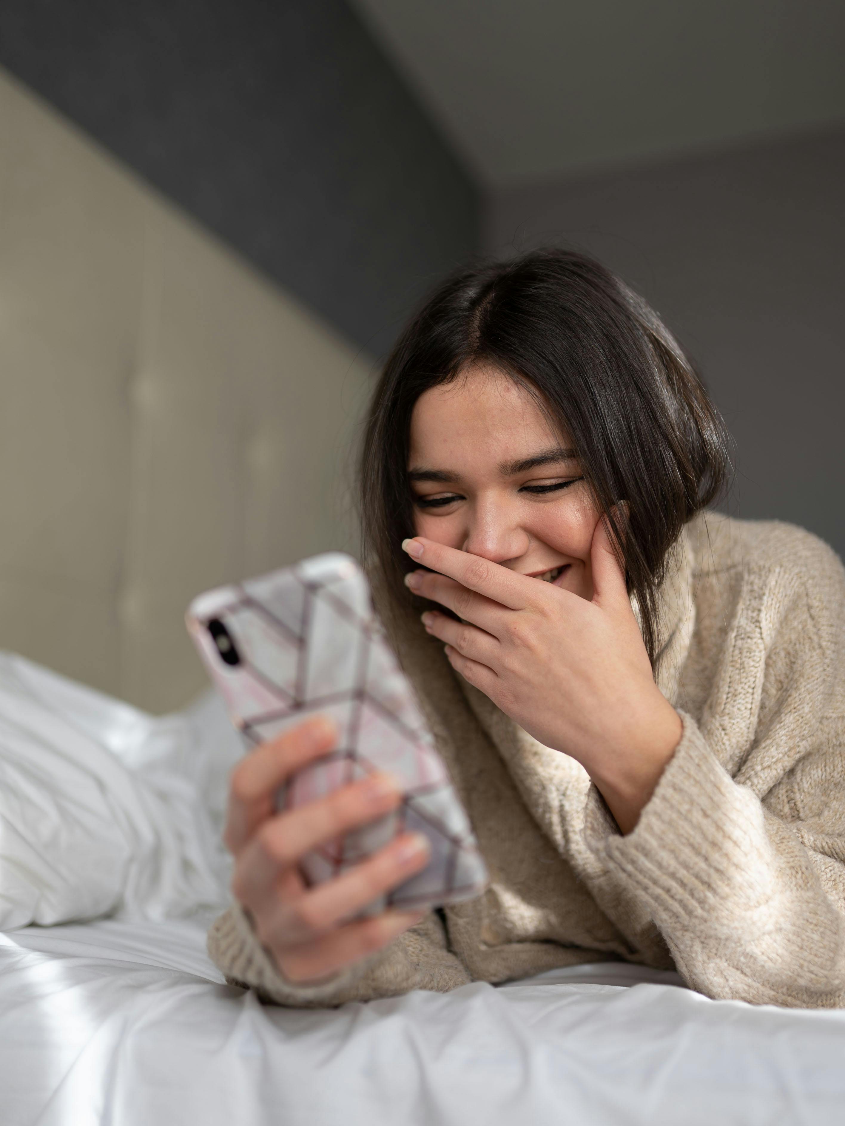 Una mujer feliz usando su teléfono | Fuente: Pexels