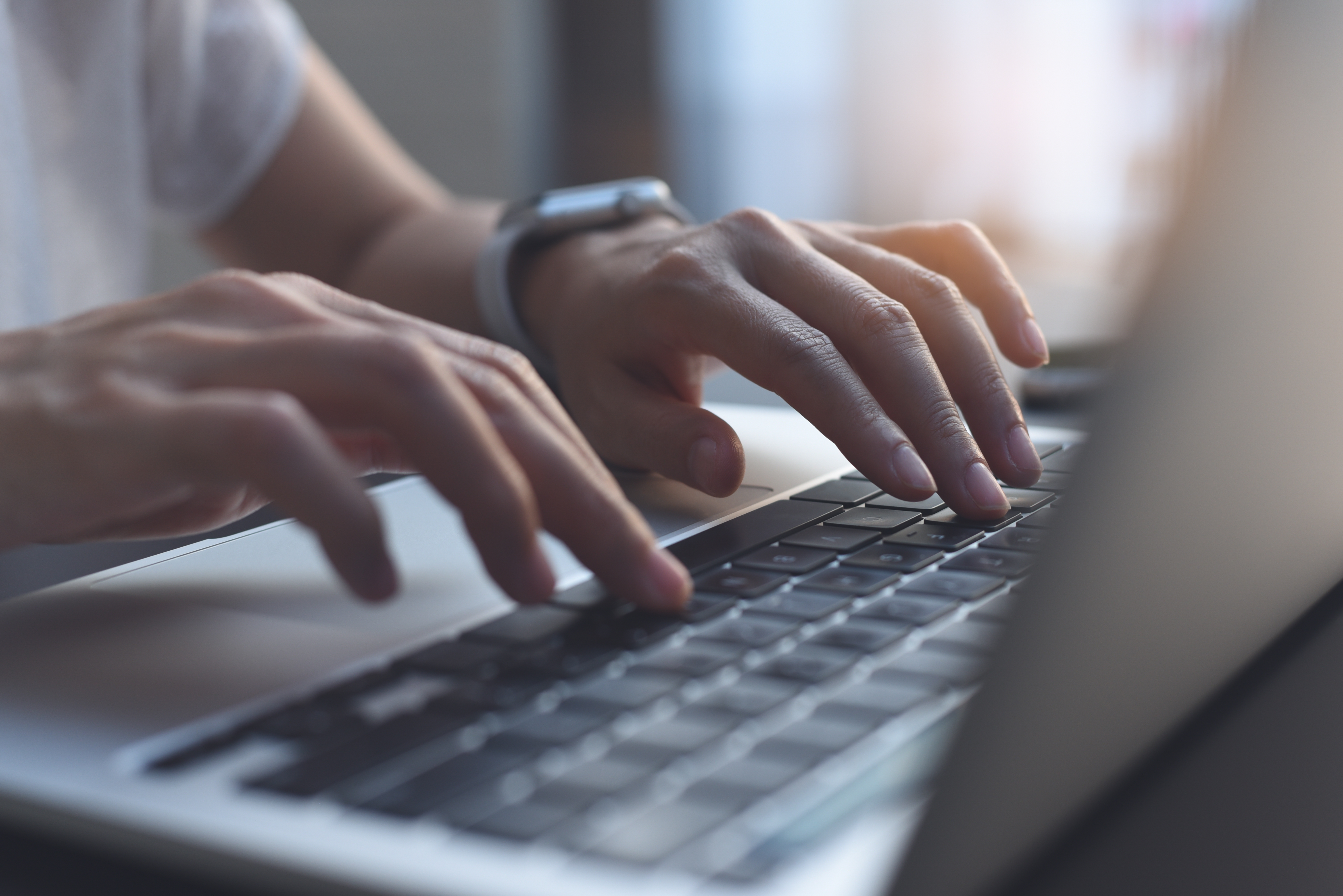 Imagen de cerca de unas manos de mujer escribiendo en el teclado de un ordenador portátil. | Fuente: Shutterstock