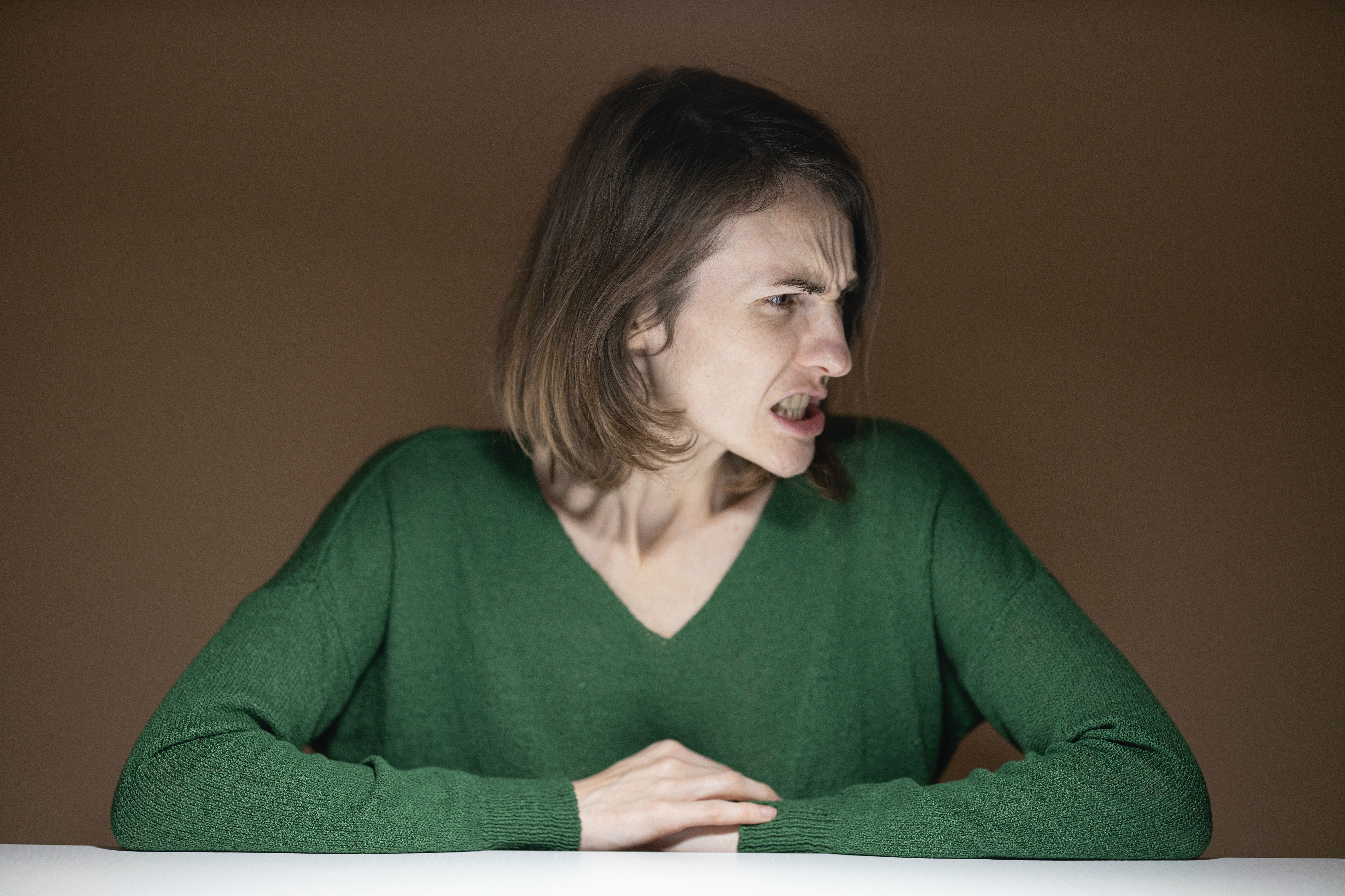 Mujer con rostro enojado vistiendo un suéter verde. | Foto: Pexels