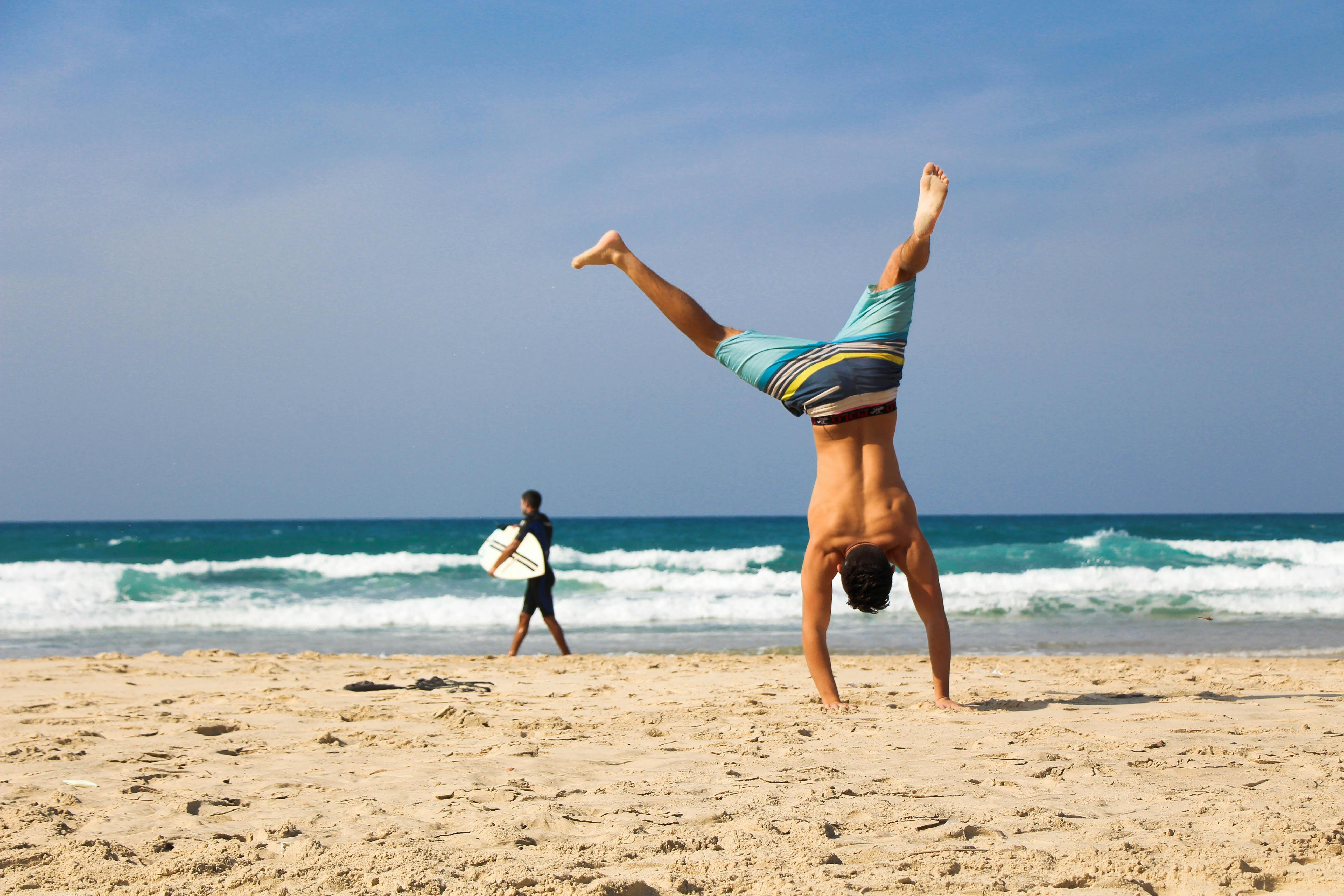 Hombre haciendo el pino en una playa | Fuente: Pexels