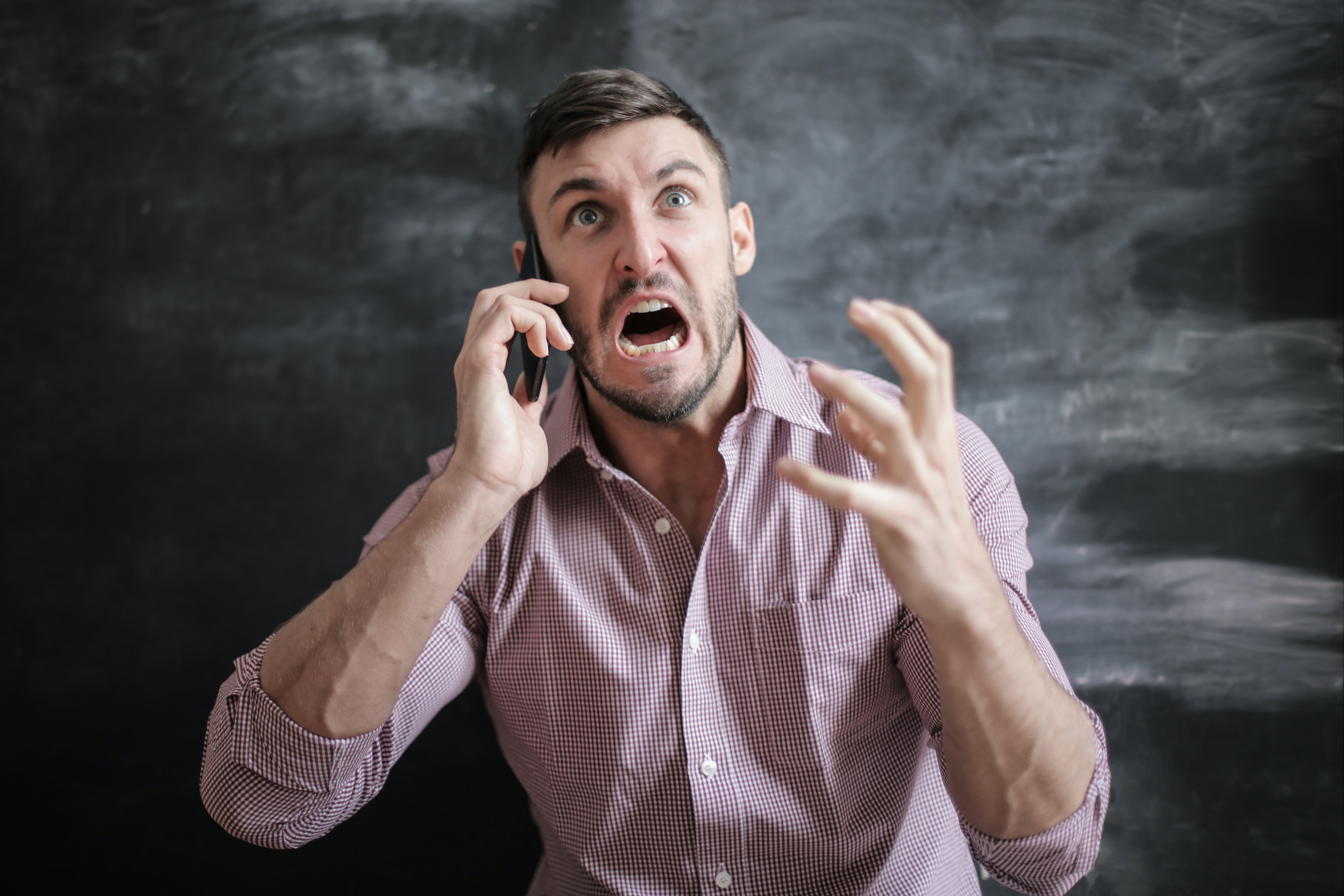 Un hombre grita mientras gesticula airadamente durante una llamada telefónica | Fuente: Pexels