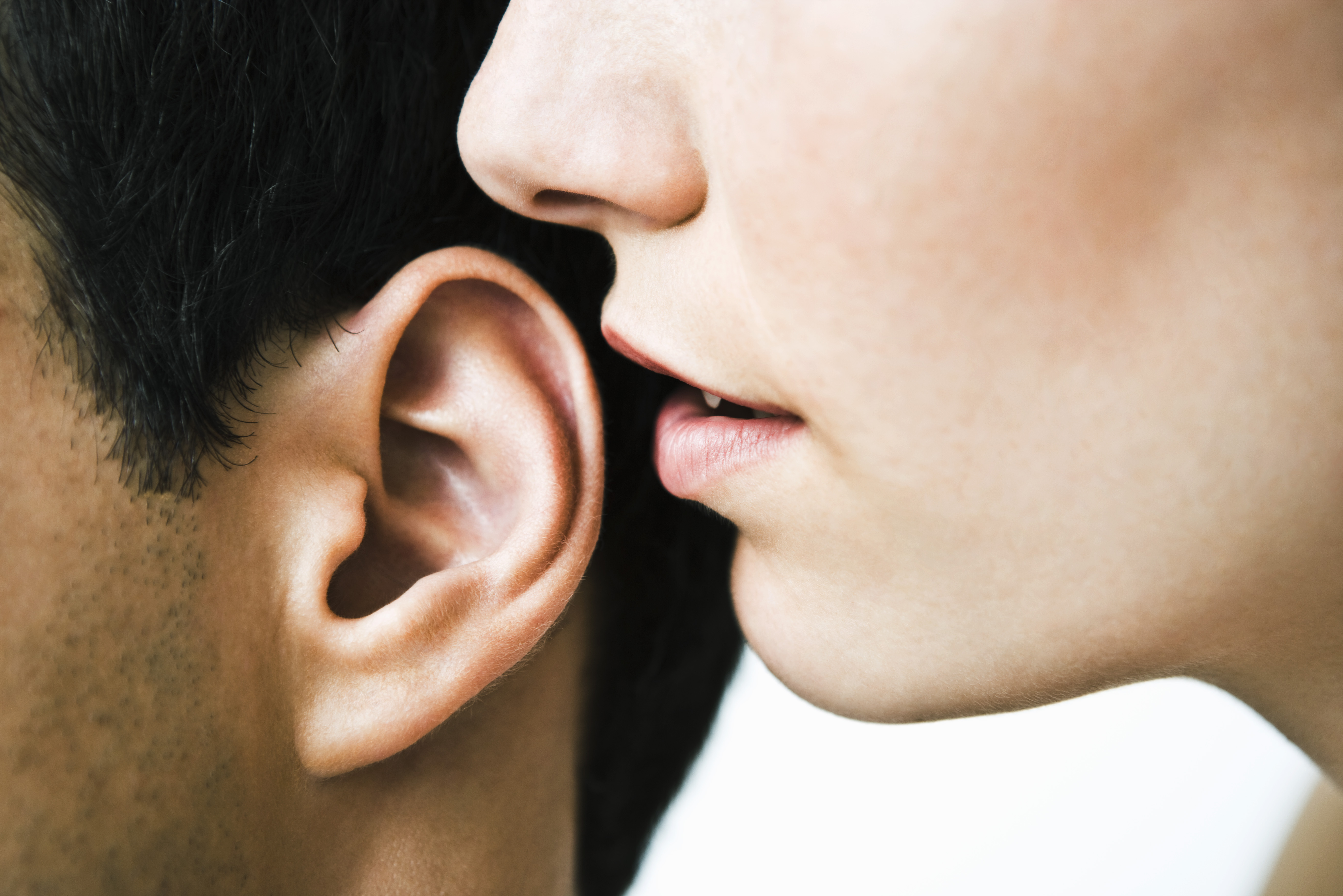 Mujer susurrando al oído de un hombre | Foto: Getty Images