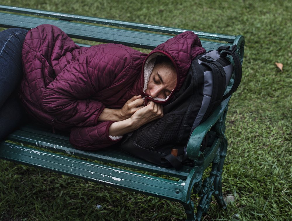 Mujer indigente durmiendo en el banco de un parque público. | Foto: Shutterstock.