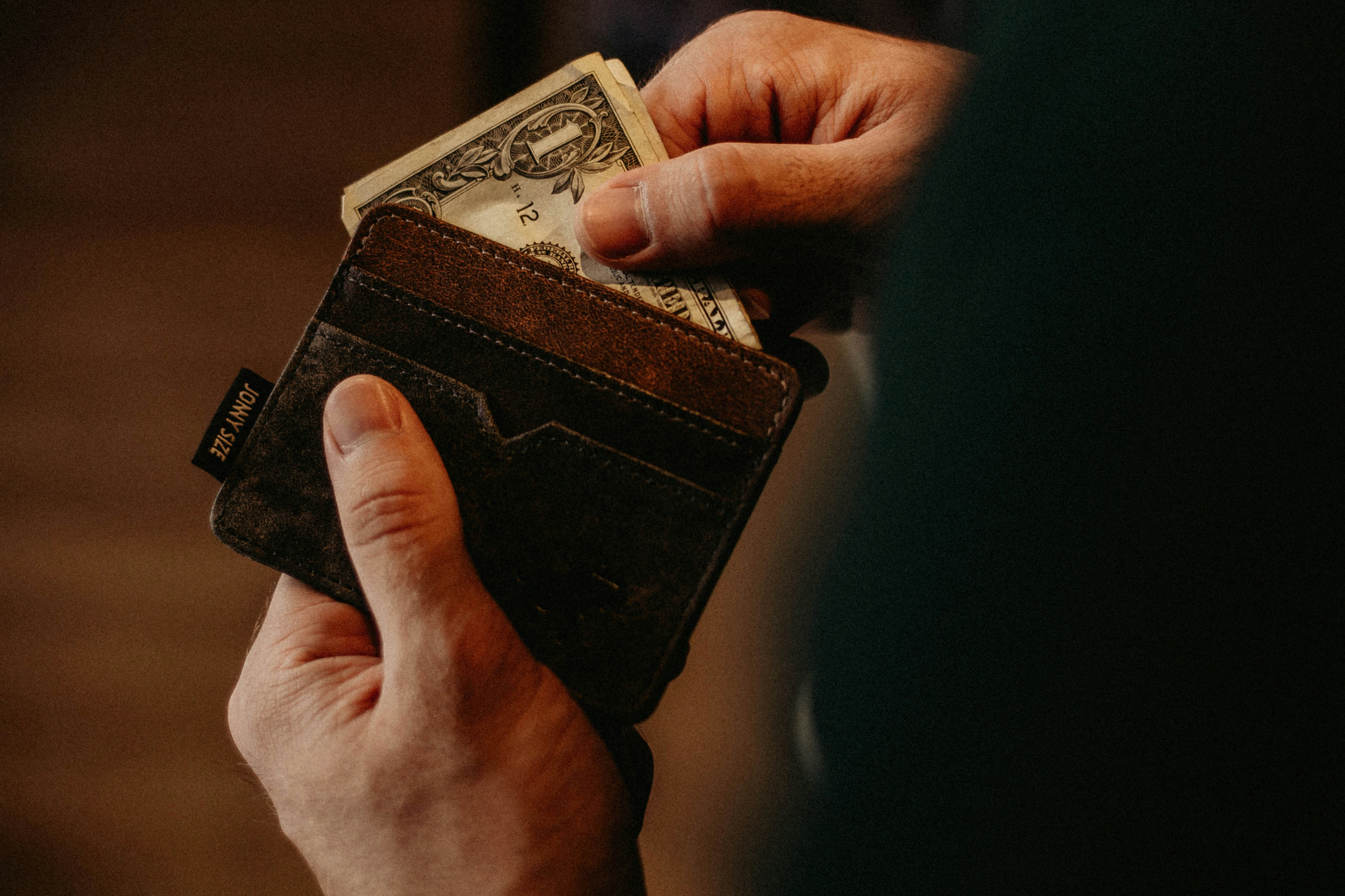 Una persona sacando dinero de su cartera | Fuente: Unsplash