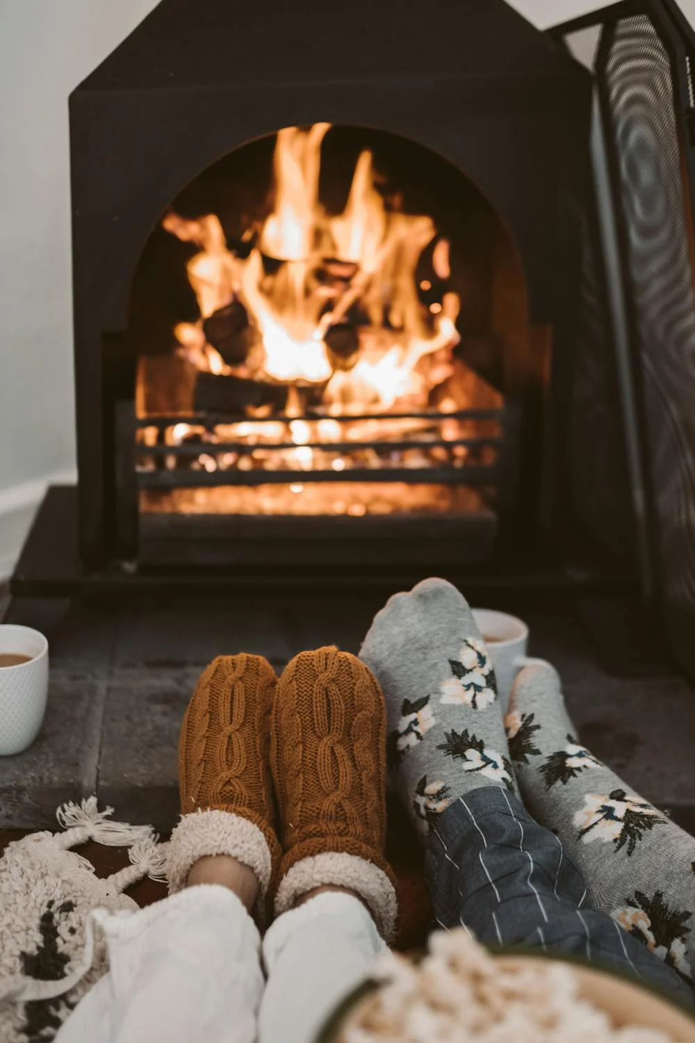 Dos pares de pies con calcetines delante de una chimenea encendida | Fuente: Pexels