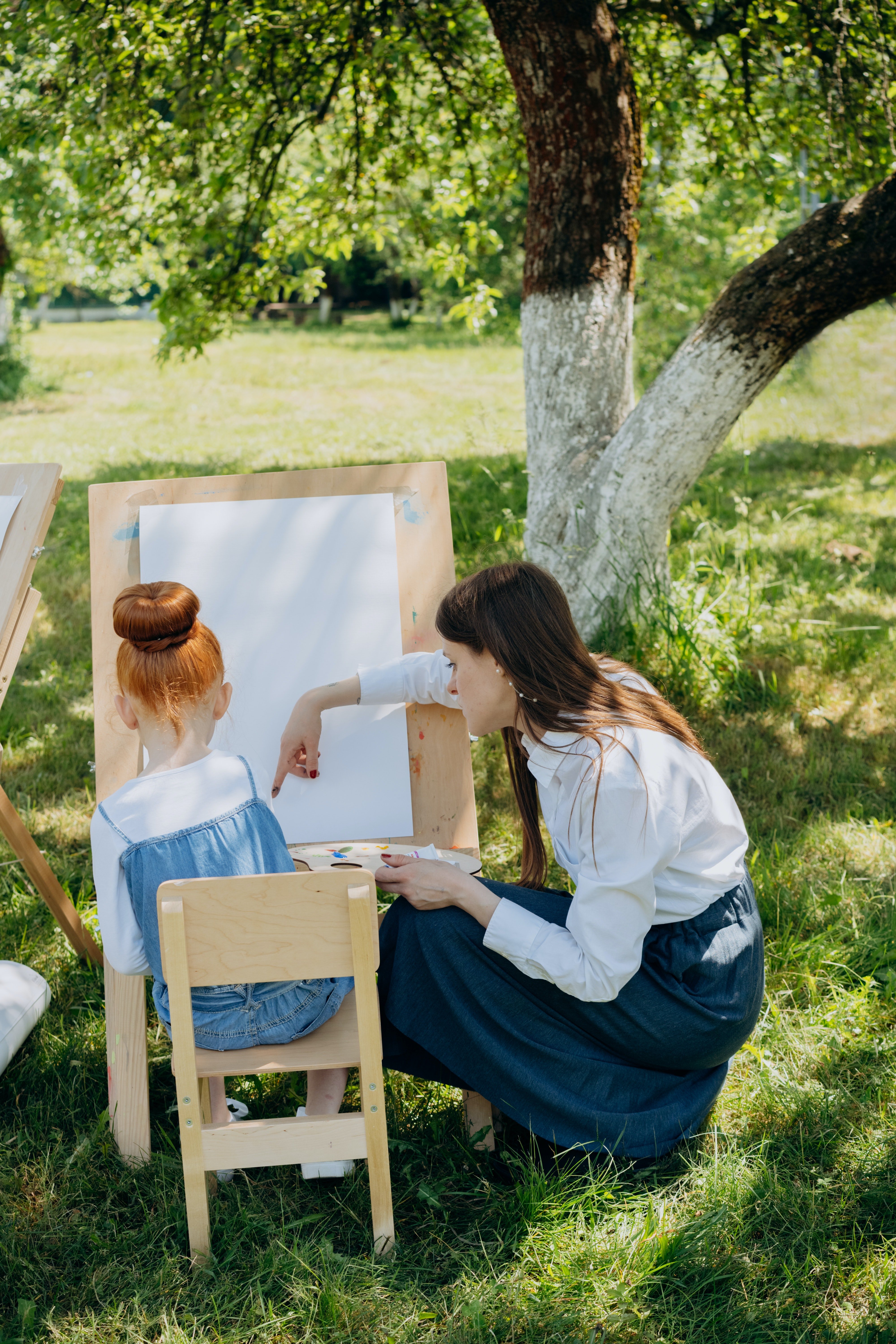 Mujer enseñando a una niña a pintar. | Foto: Pexels