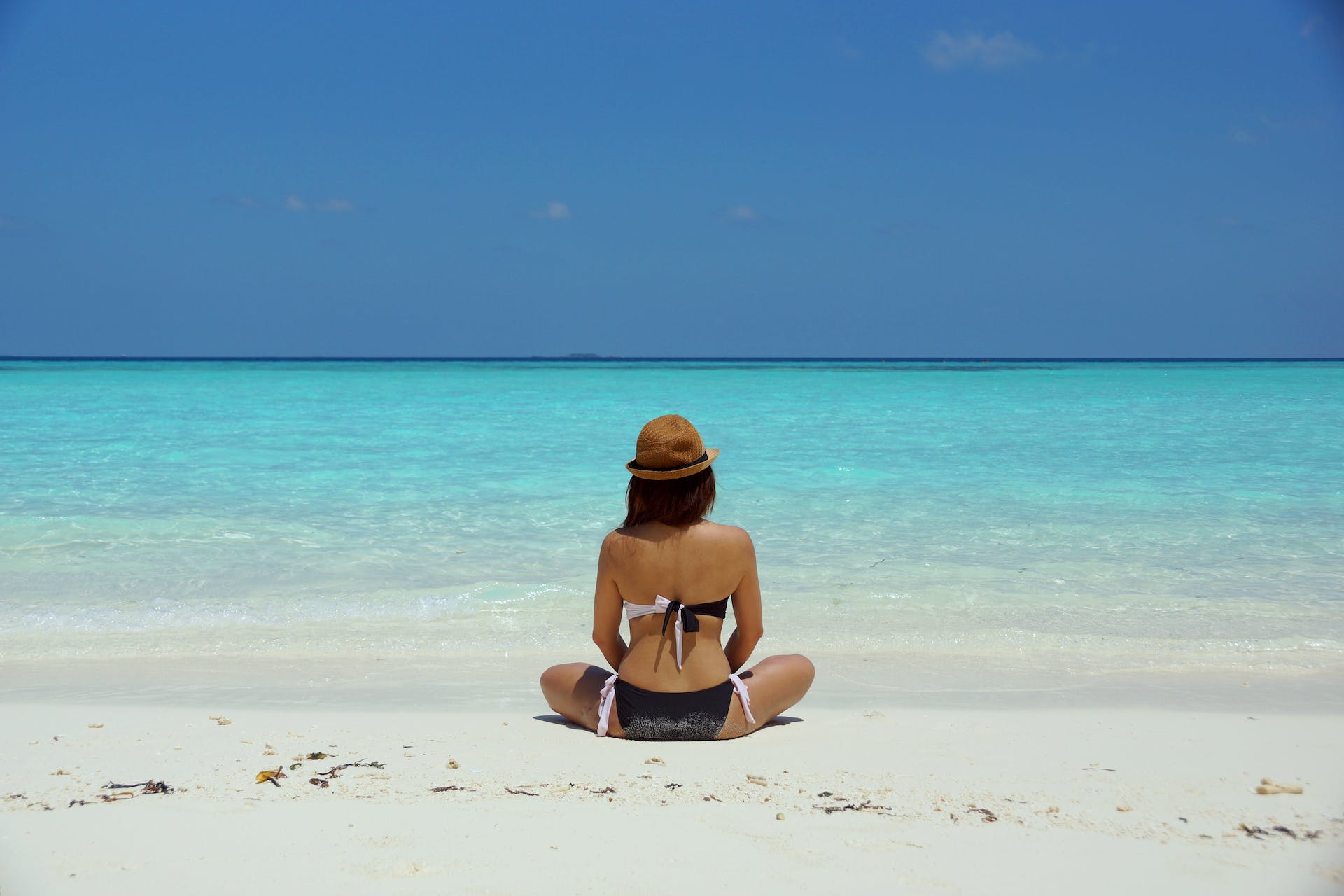 Mujer sentada en la playa en bikini | Foto: Pexels