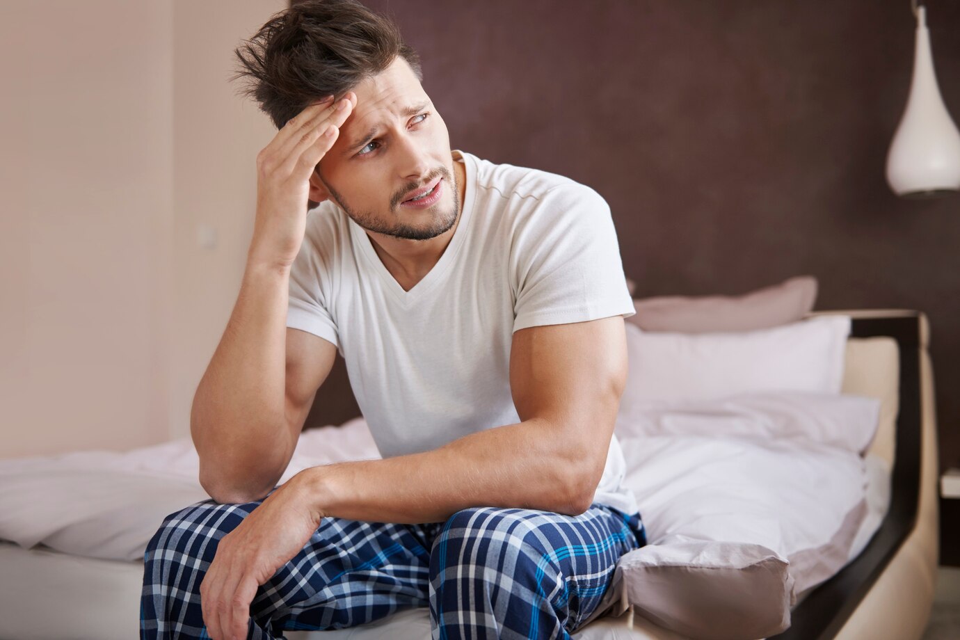 Un hombre cansado y perplejo sentado en su cama | Fuente: Freepik