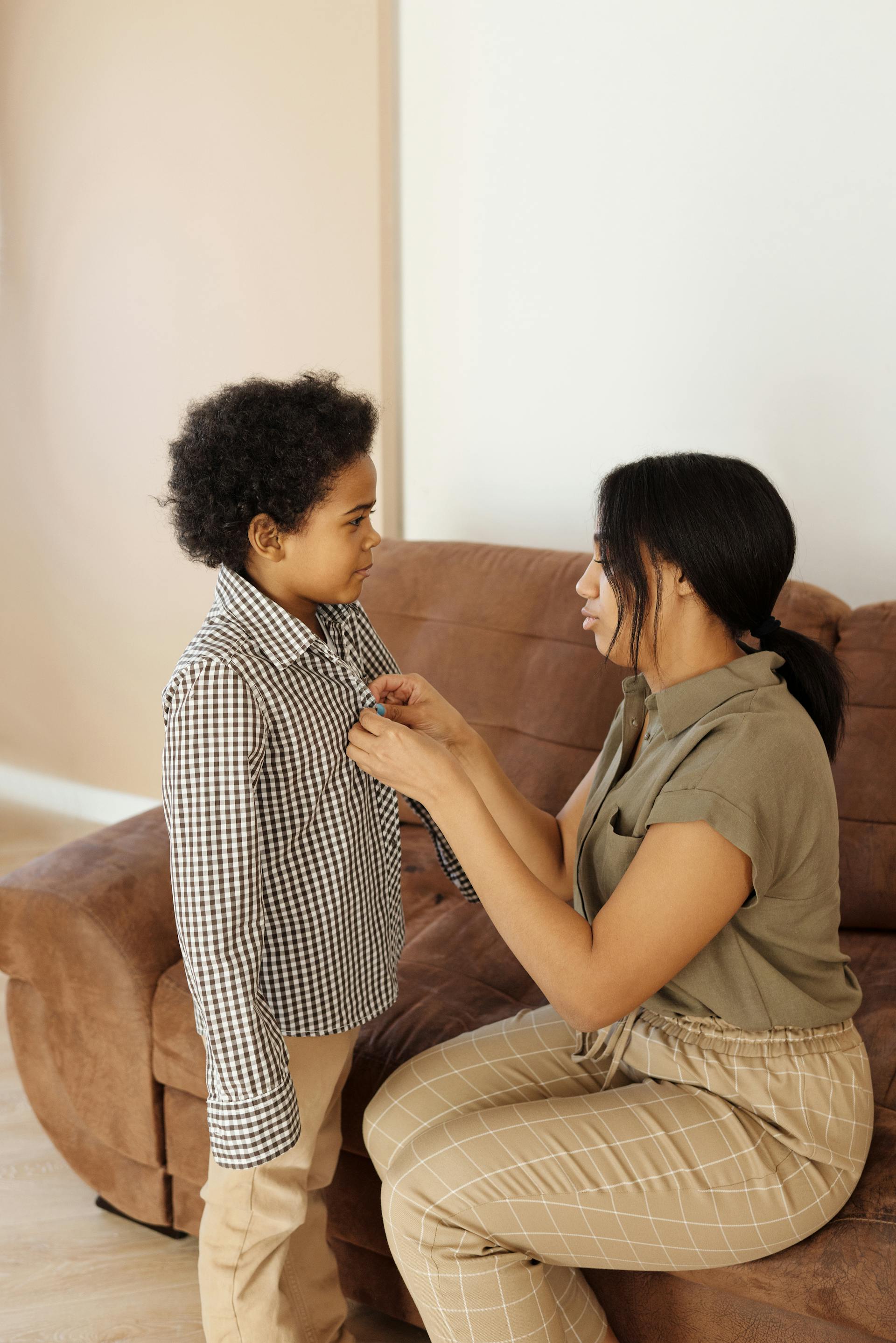 Una madre ayudando a su hijo a vestirse | Fuente: Pexels