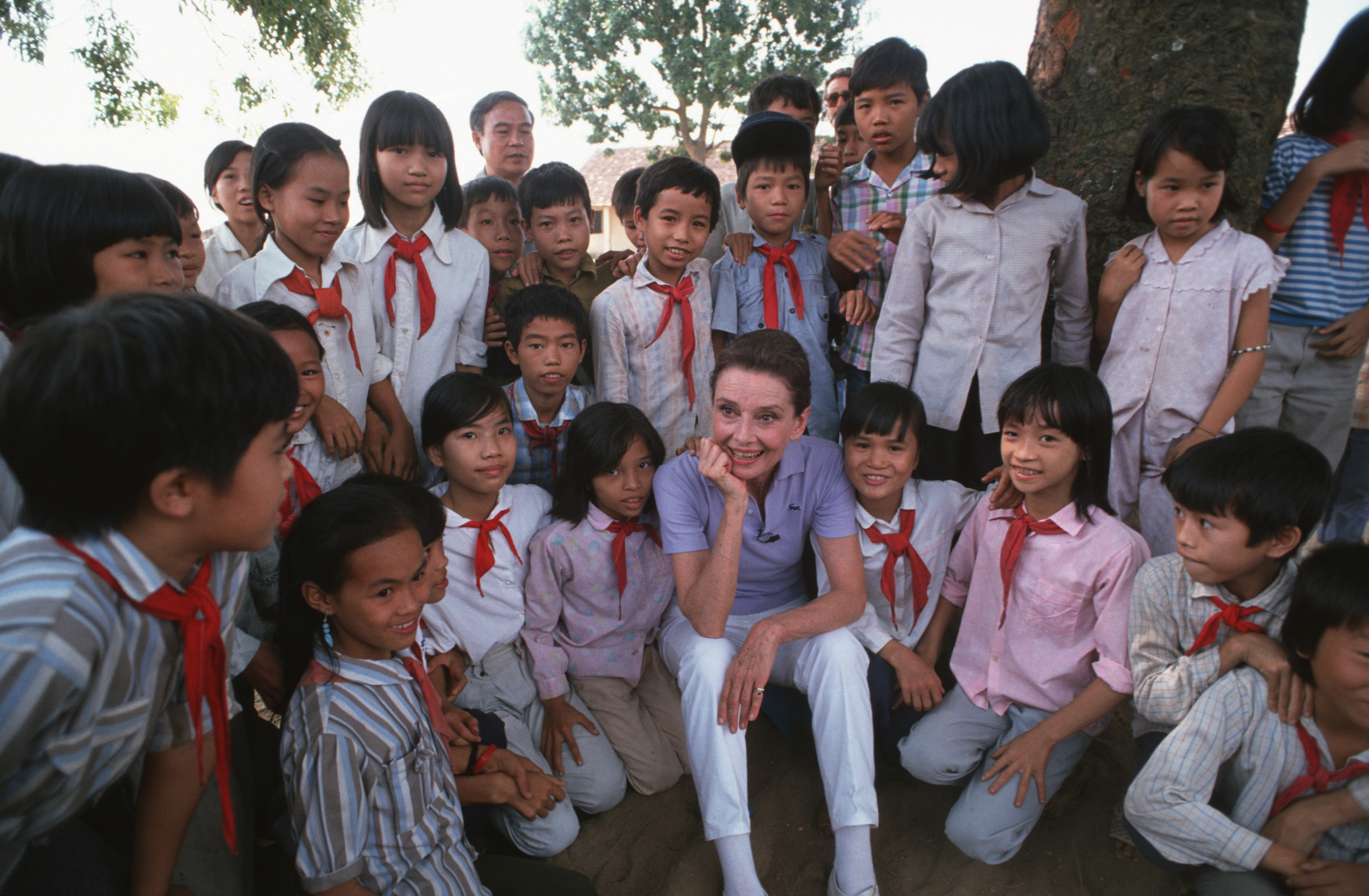 Audrey Hepburn se toma su tiempo para conocer a unos escolares de uniforme en un pequeño pueblo cerca de Hanoi el 1 de octubre de 1990 | Fuente: Getty Images